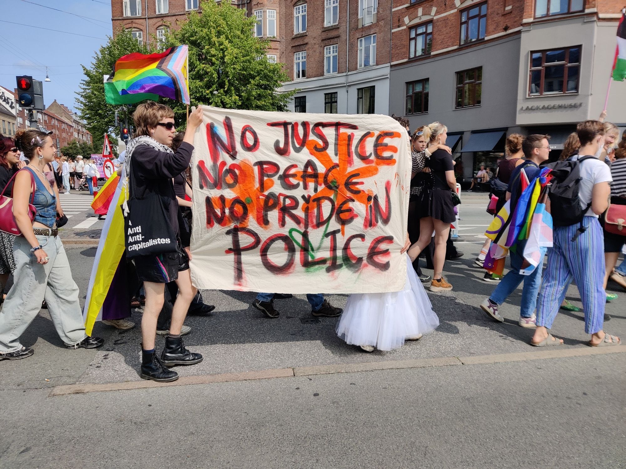 Queer people holding up a banner that reads: no justice no peace. No pride in police