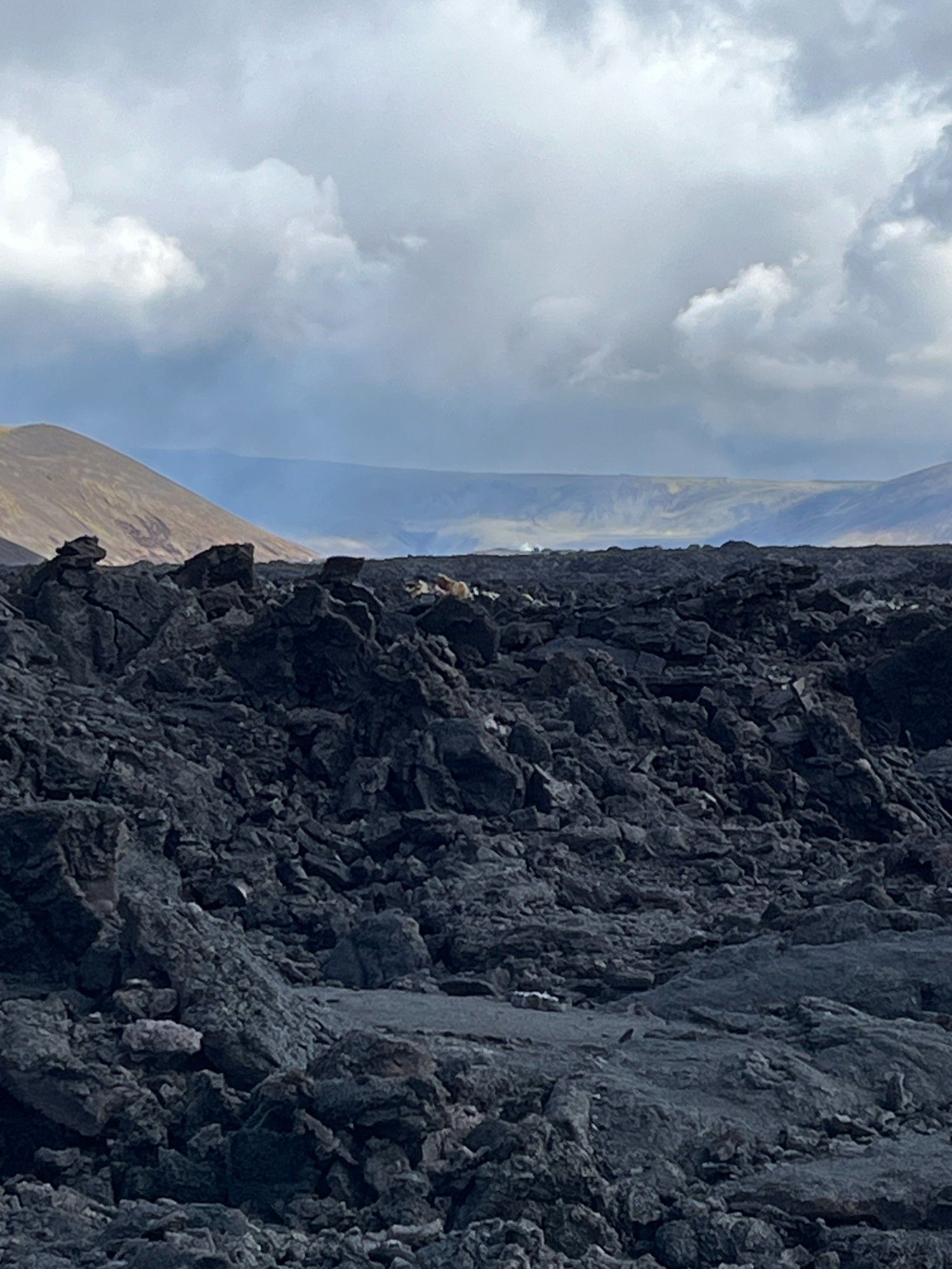 A lava field with cooling lava in the background