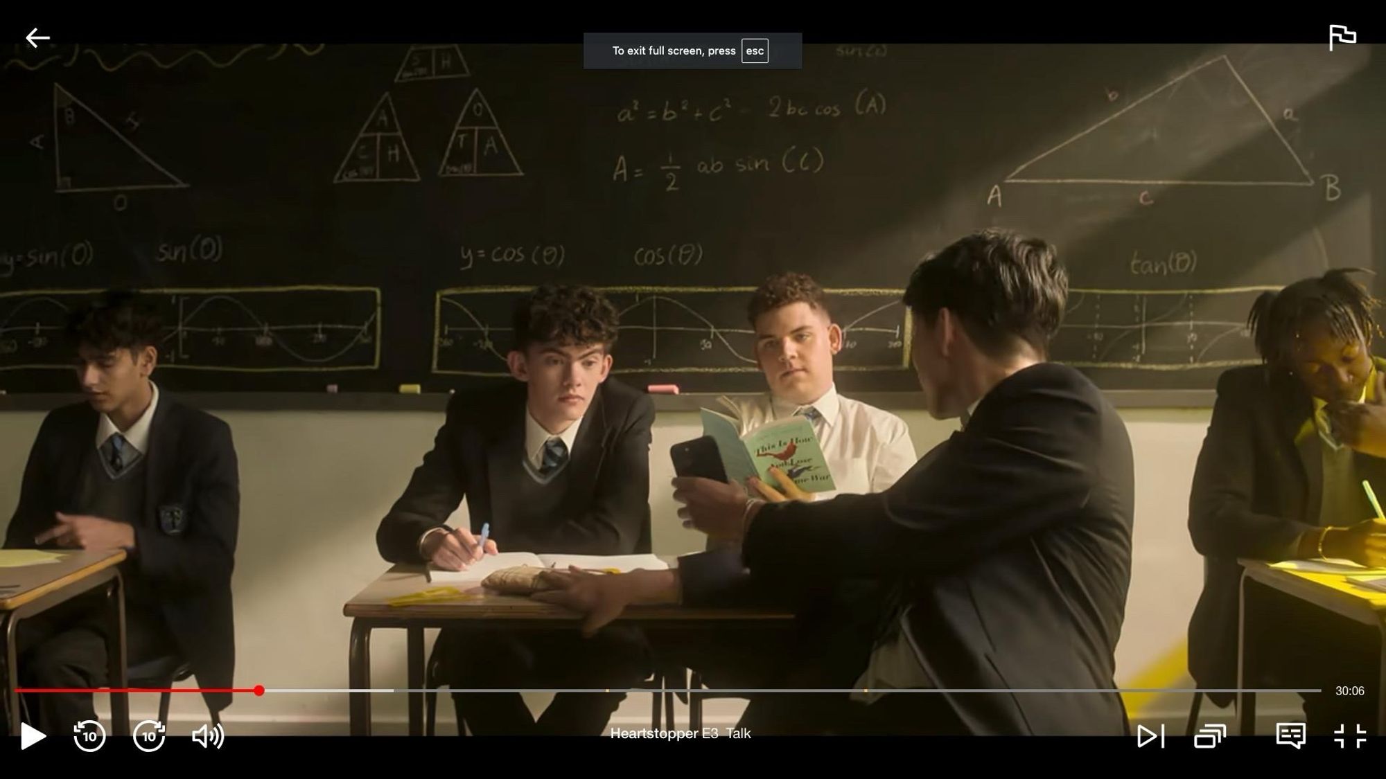 Screenshot of another scene from Heartstopper, in a classroom, with the same boy reading the same book.