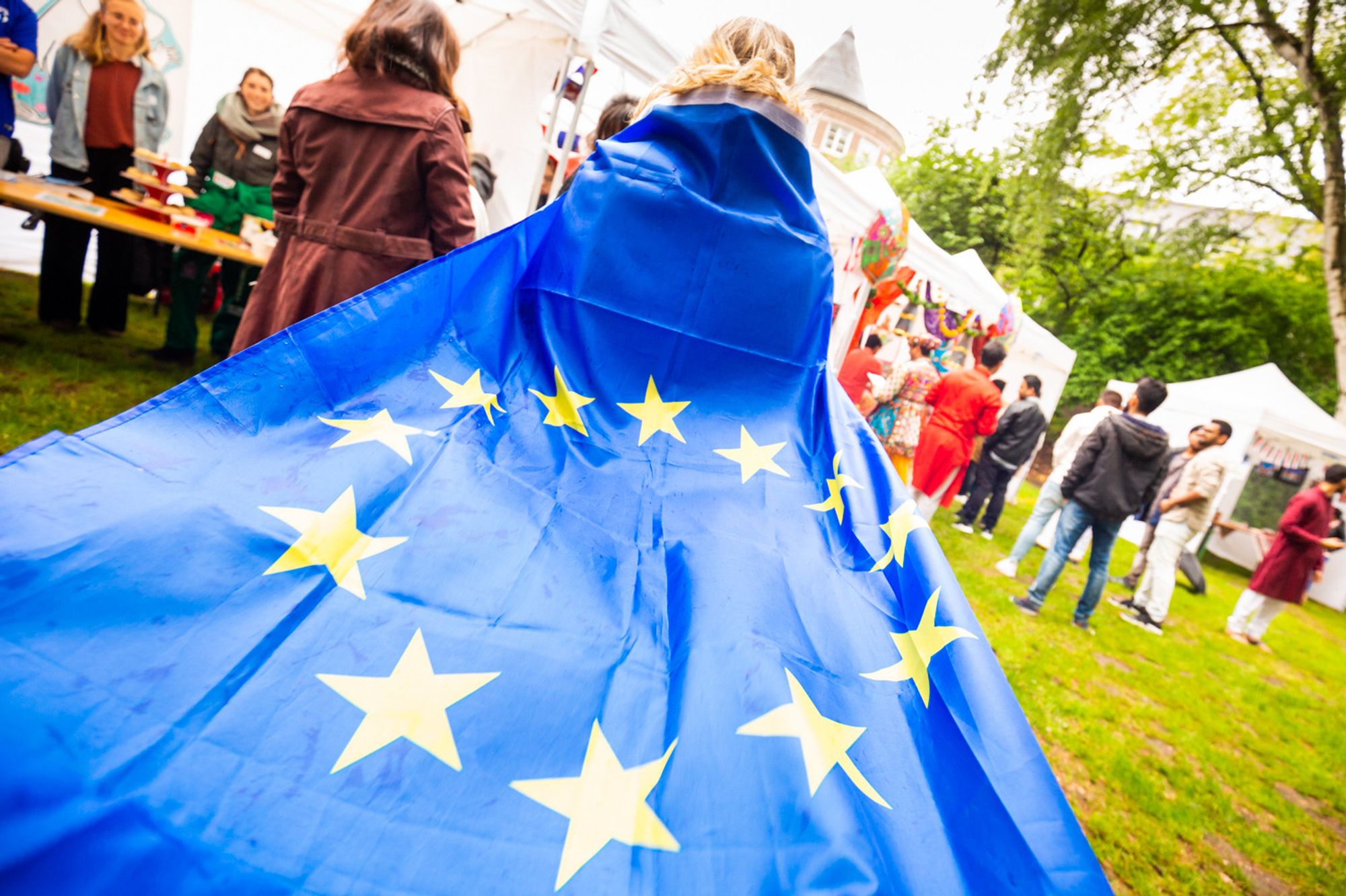 Eine Person, die sich eine EU-Fahne um die Schultern gelegt hat und sie wie eine Schleppe trägt.