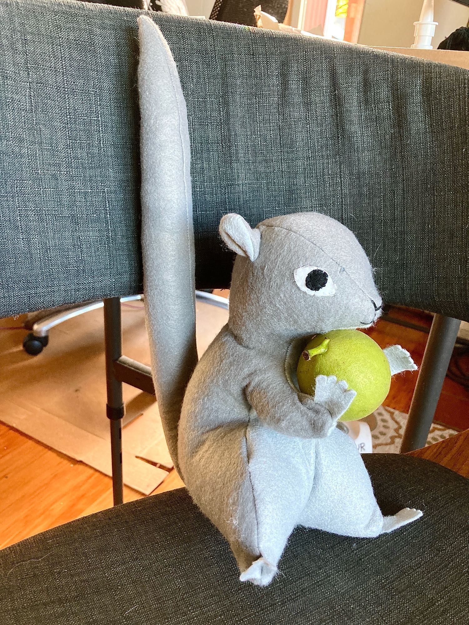 A hand sewn stuffy squirrel holding a fresh walnut from the backyard