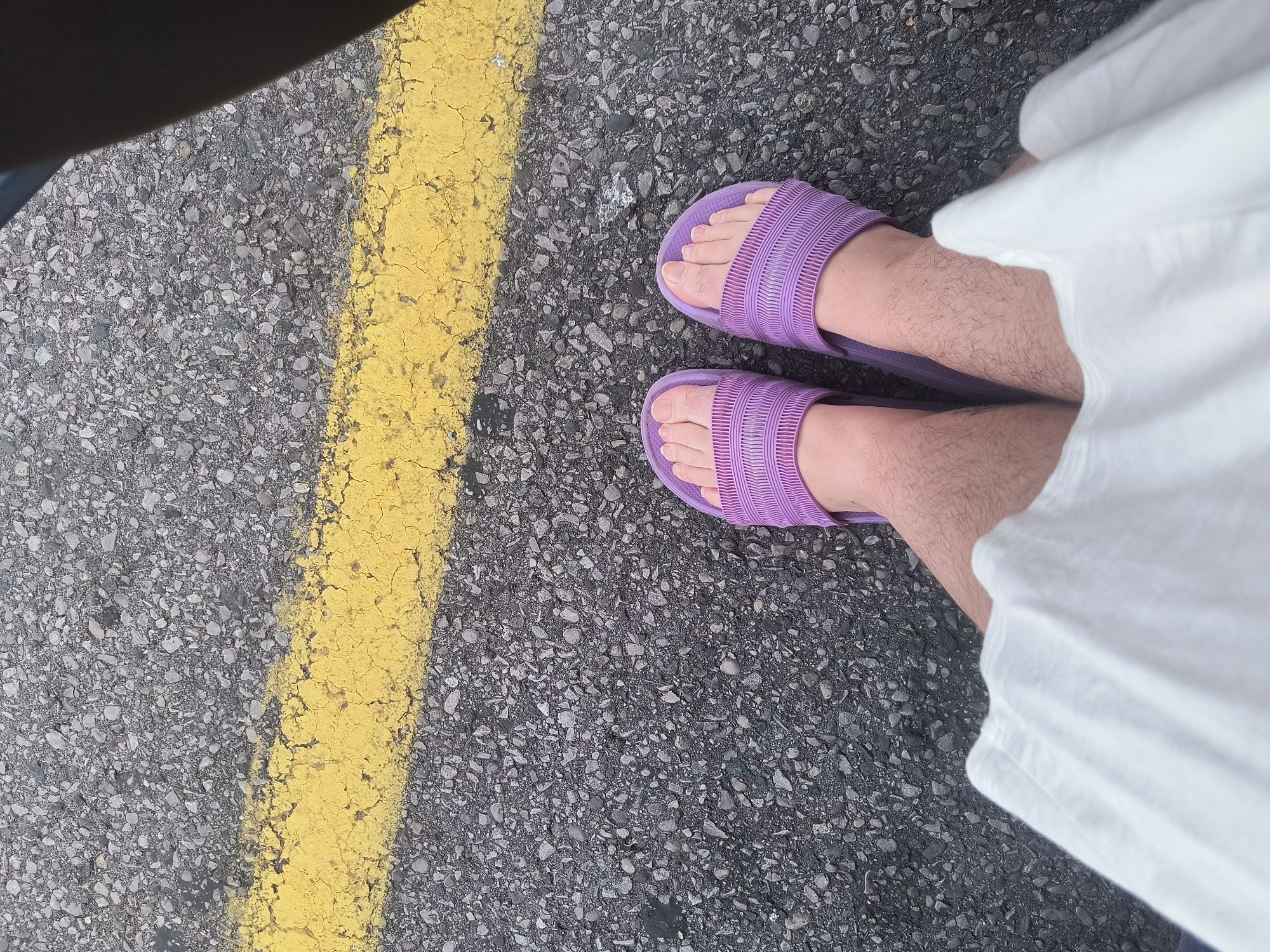 A pair of feet wearing purple rubber slides.