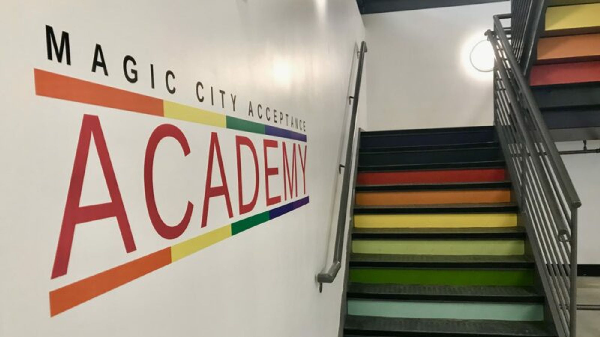 A wall at the Magic City Acceptance Academy showing their logo and some rainbow stairs going upwards.