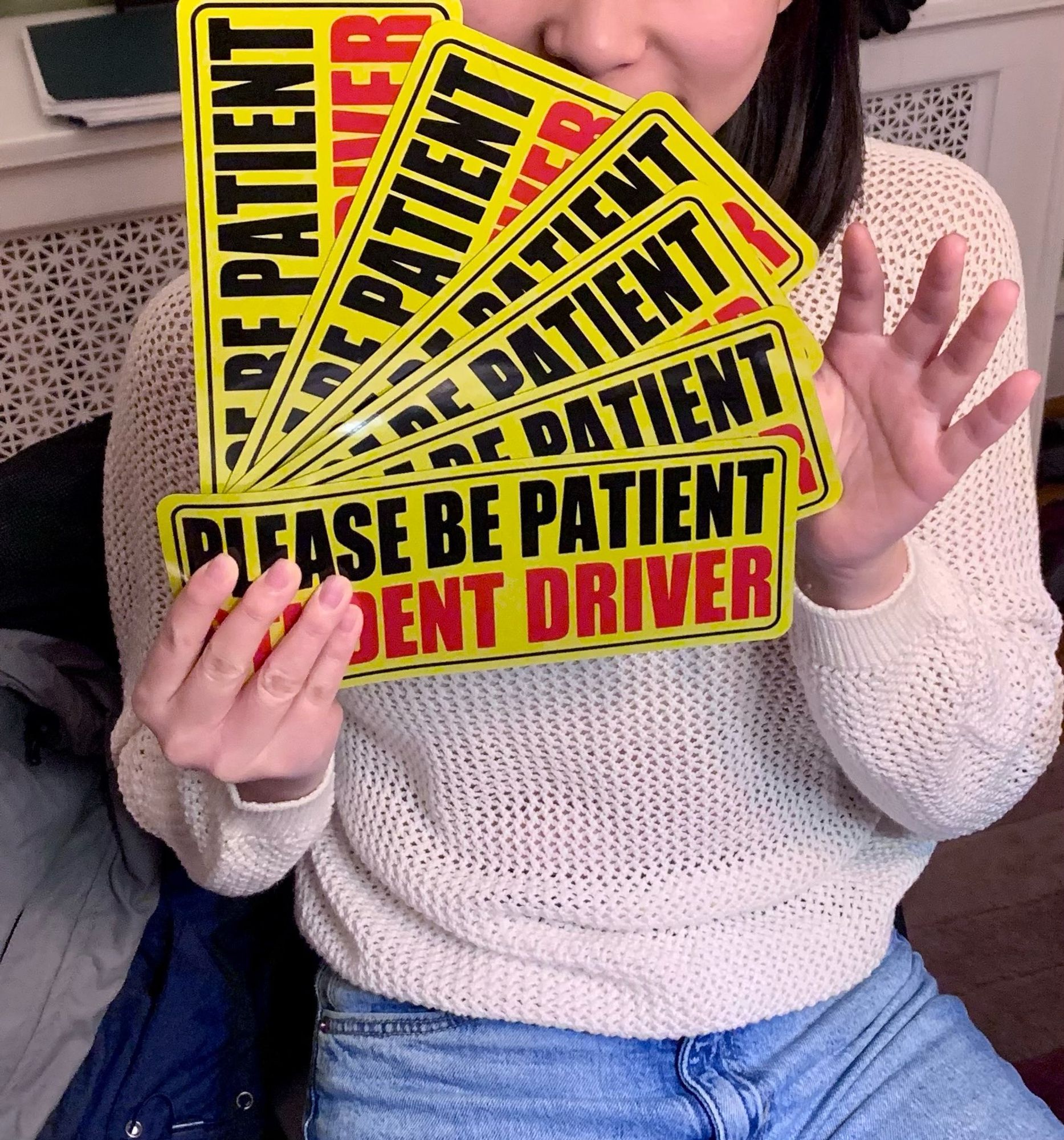 A 17 years old girl is holding four car magnets for student driver. She got a permit.