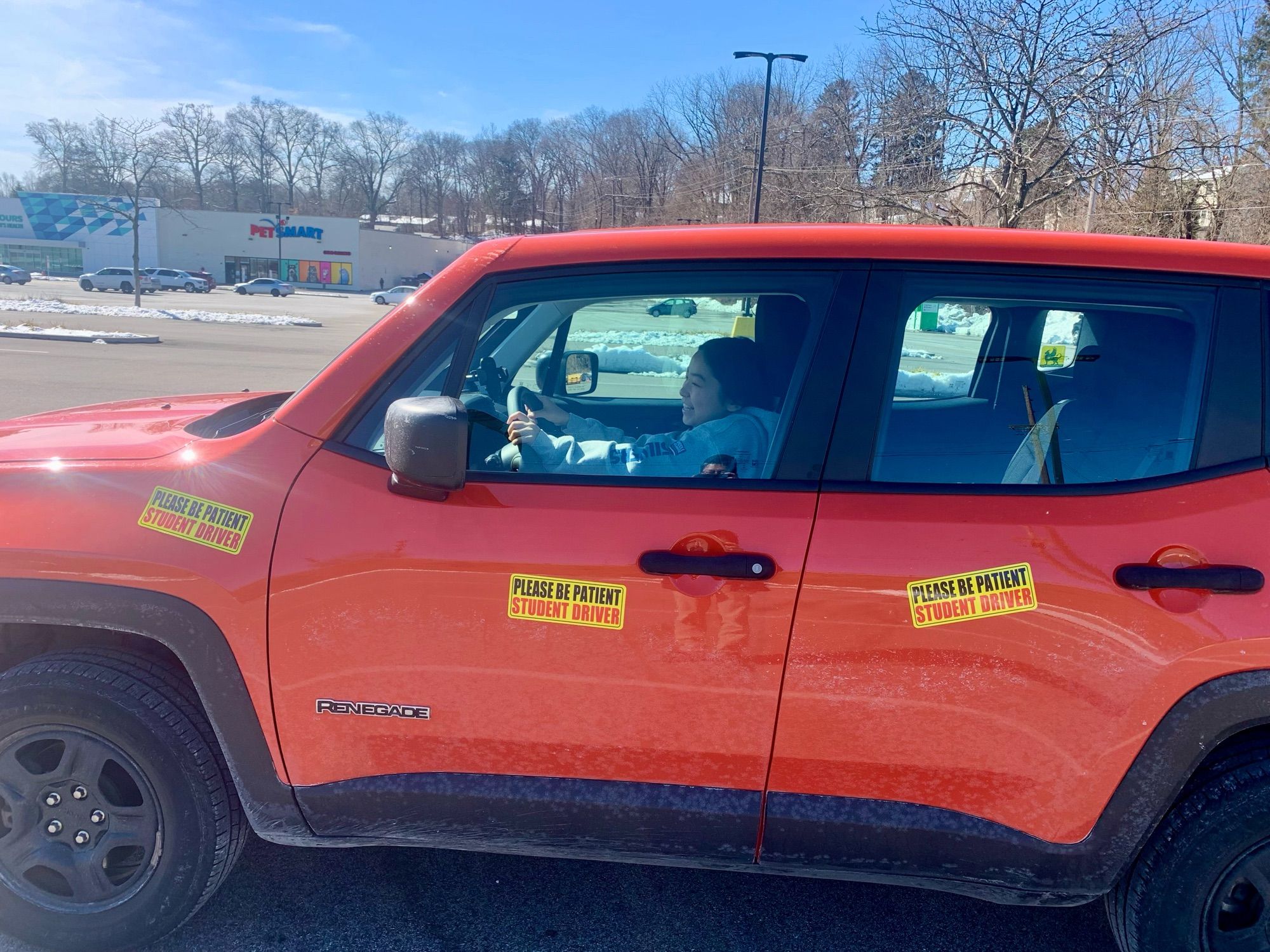 A 17 years old girl in an orange car that shows multiple signs of “Student Driver”.