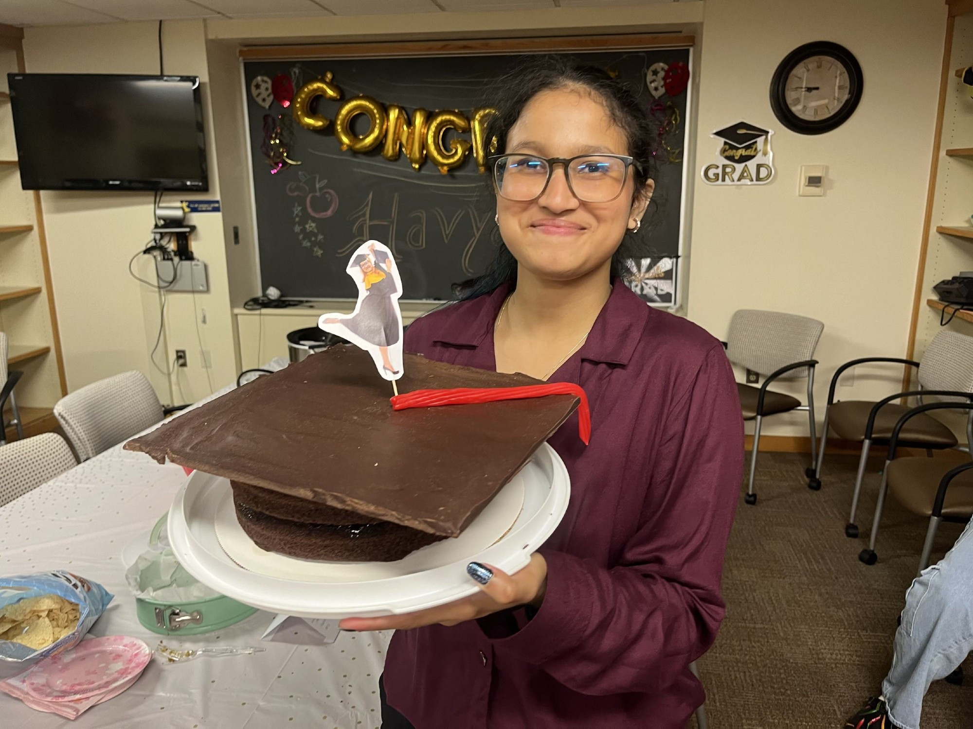 Havya is holding the chocolate graduation cap.