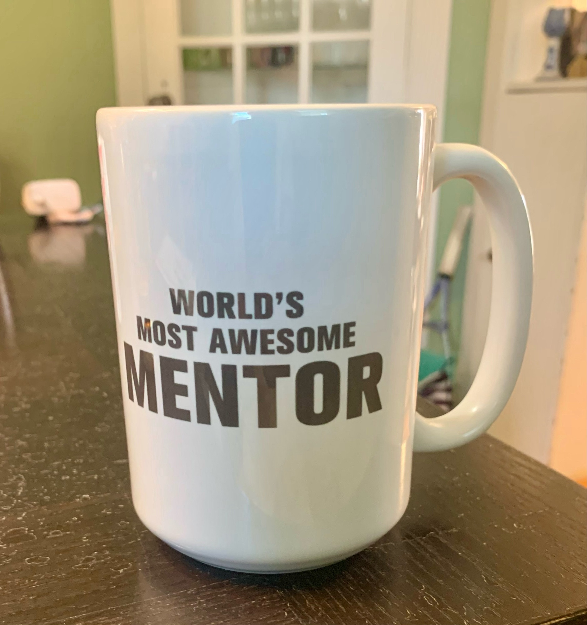 A white mug says world’s most awesome mentor.