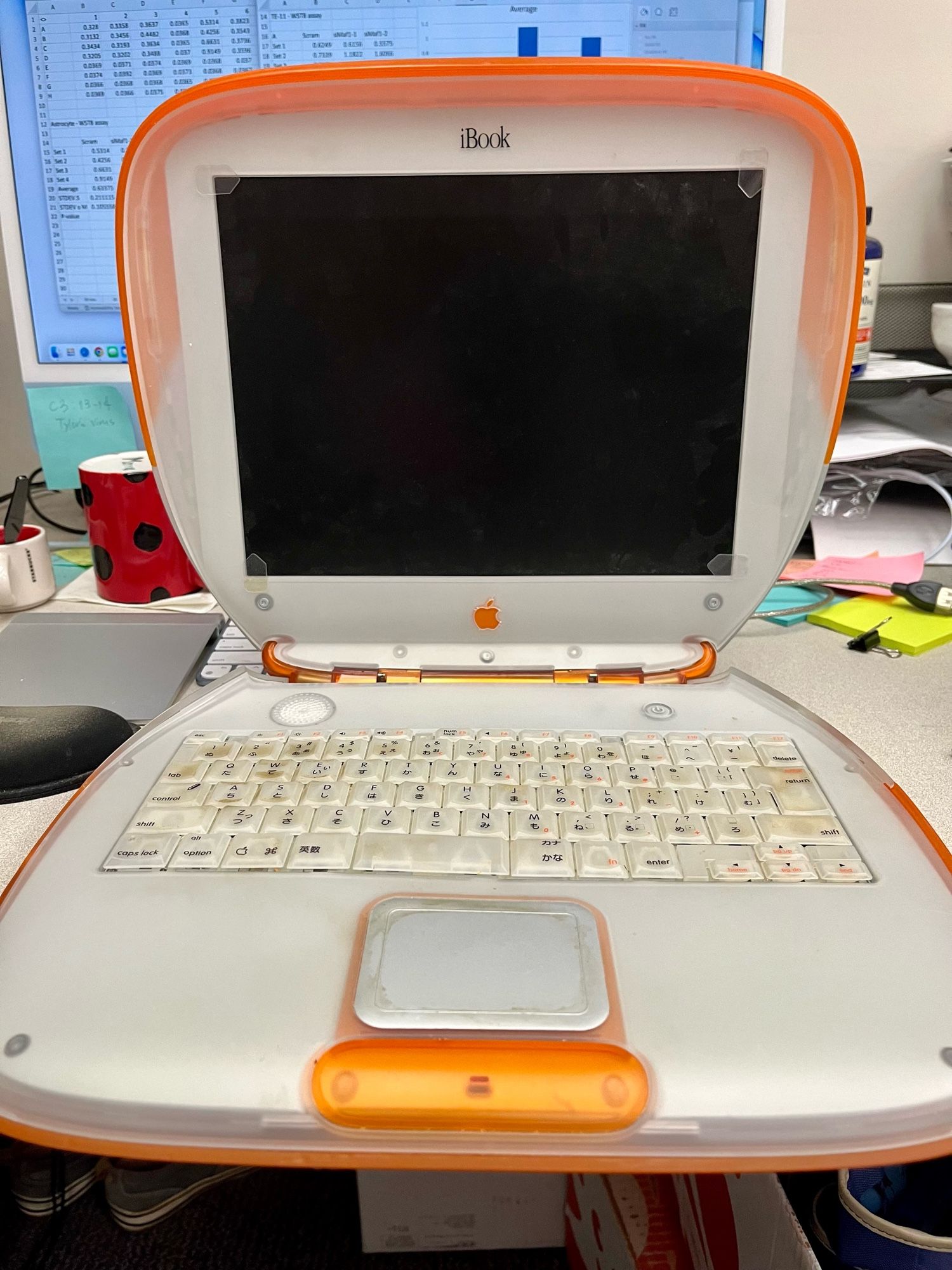 An orange iBook is open on a desk.