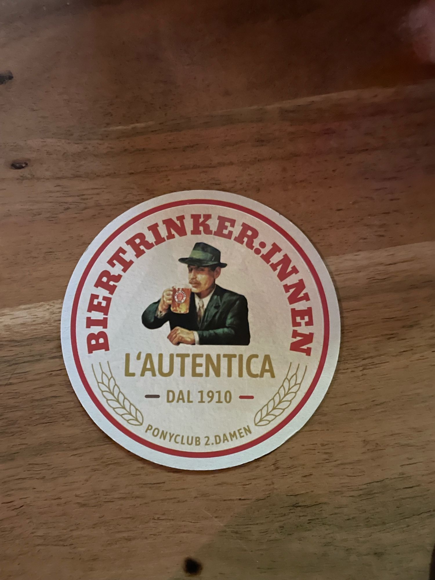 Biertrinker:innen L‘autentica dal 1910 Bierdeckel auf einem Tisch in einer Freiburger Kneipe