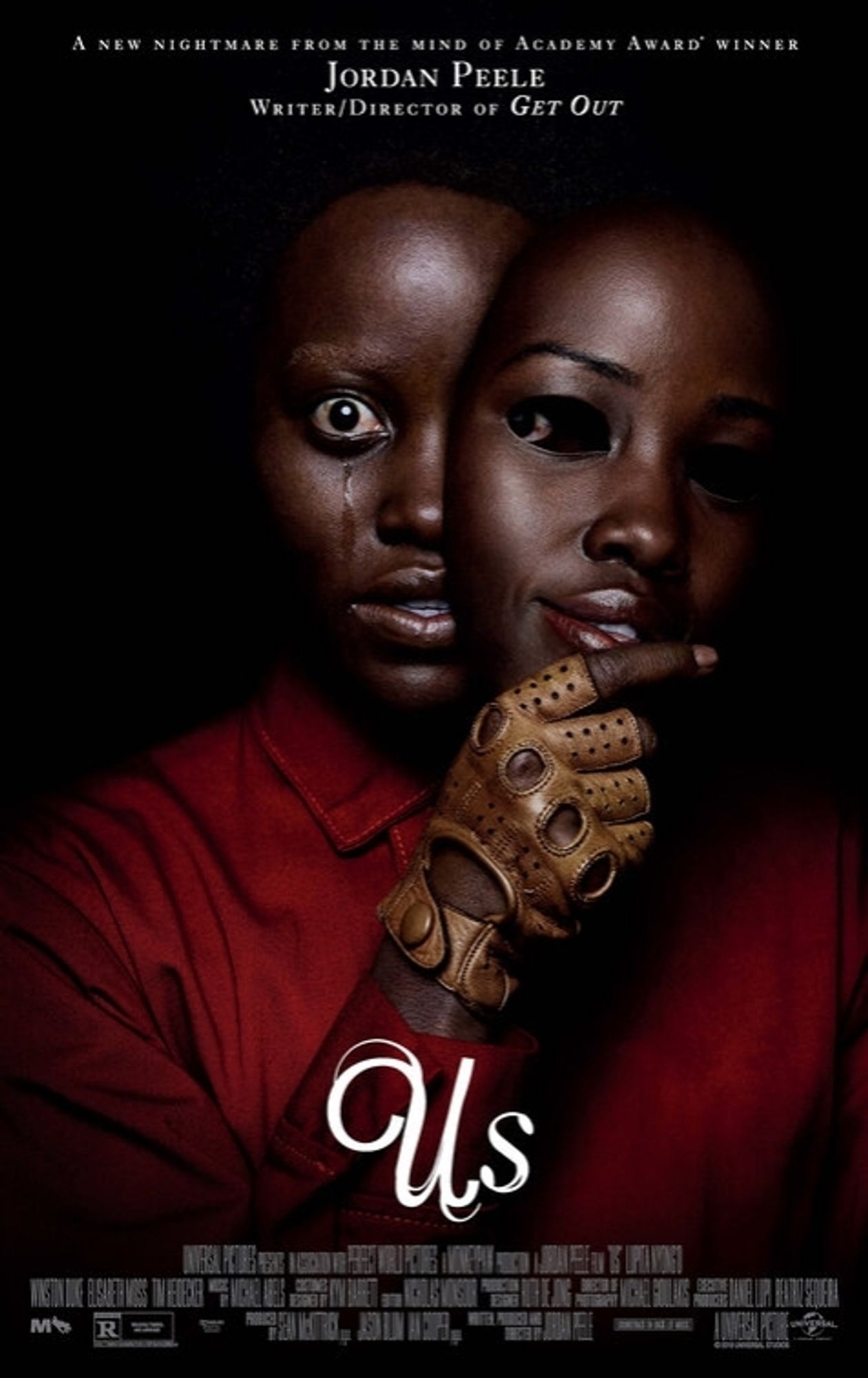 Poster for Us. Against black background, a view from torso up shows Adelaide, with finger glove and red jumpsuit, pulling a doppleganger mask of herself off of her face to the her left side. The mask has empty eye holes, and her own face shows her right eye wide open, crying. The left eye, bloodshot, is partially obscured by the mask, but its pupil is visible in the corner of thr mask eye hole, as if the mask itself is peering back