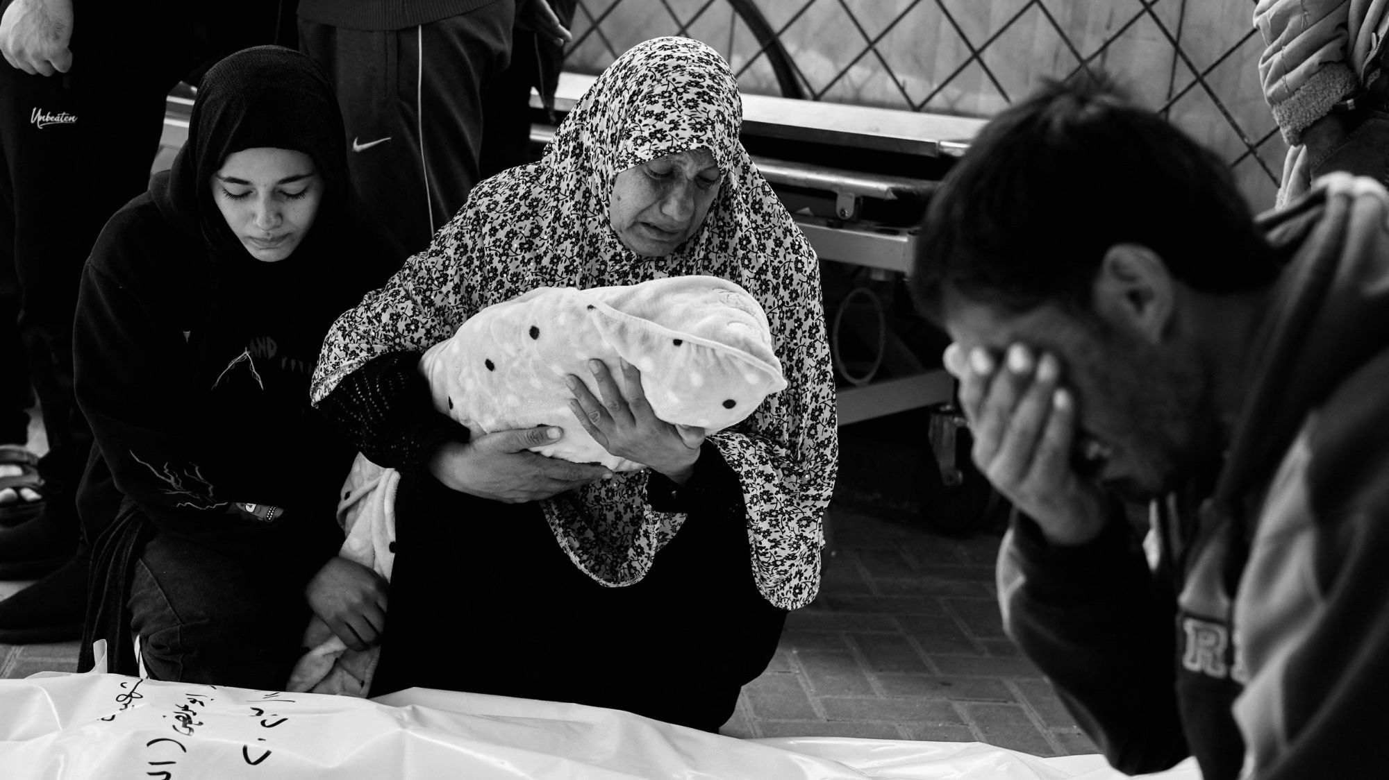 The grandmother of Palestinian baby Idres Al-Dbari, who was born during the war and killed in an Israeli strike, holds his body at Abu Yousef al-Najjar hospital, Rafah, in the southern Gaza Strip, 12 December 2023 (Reuters/Mohammed Salem)