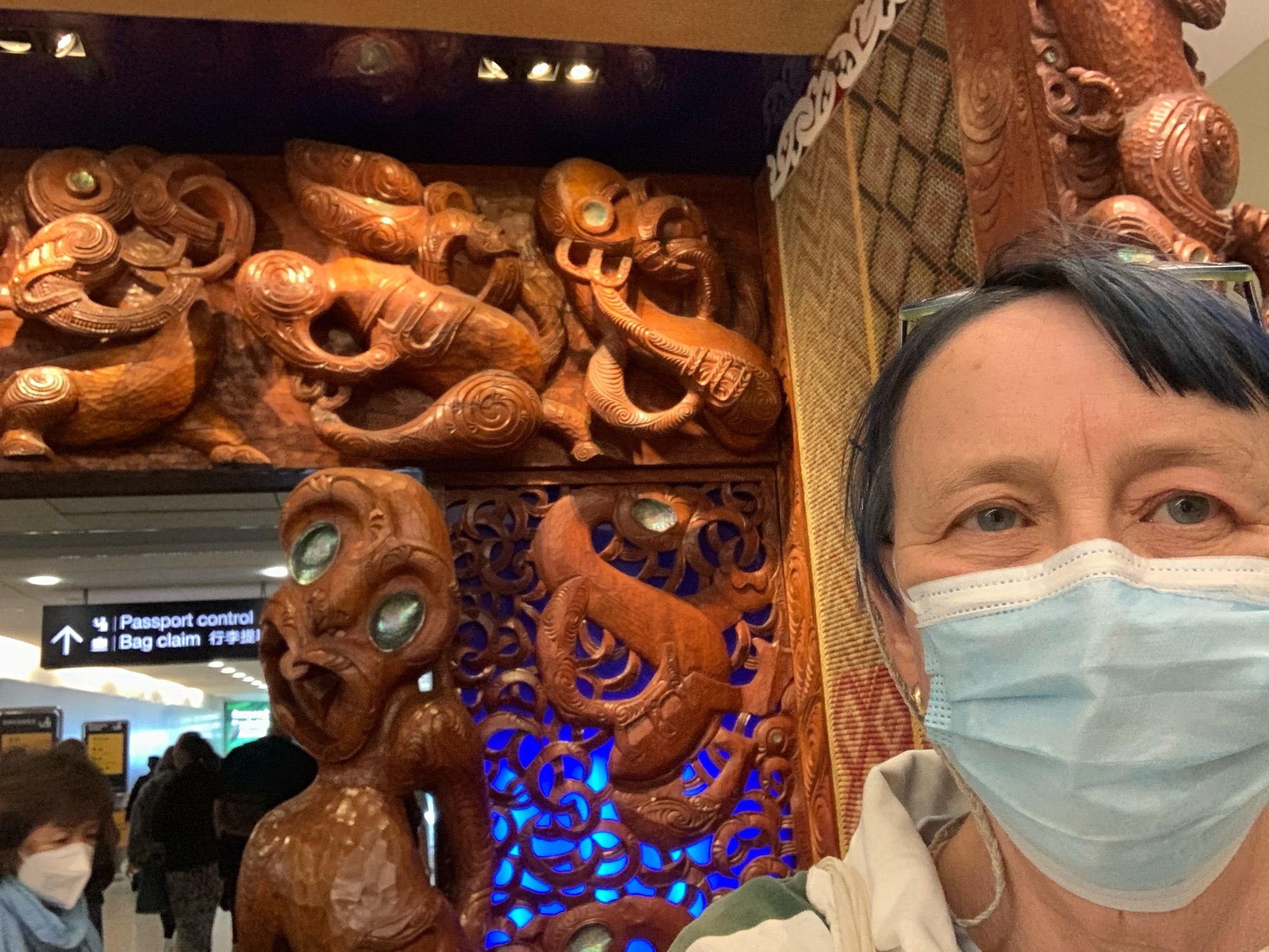 selfie at the Auckland International airport arrival gate, which is wood carving of Maori figures