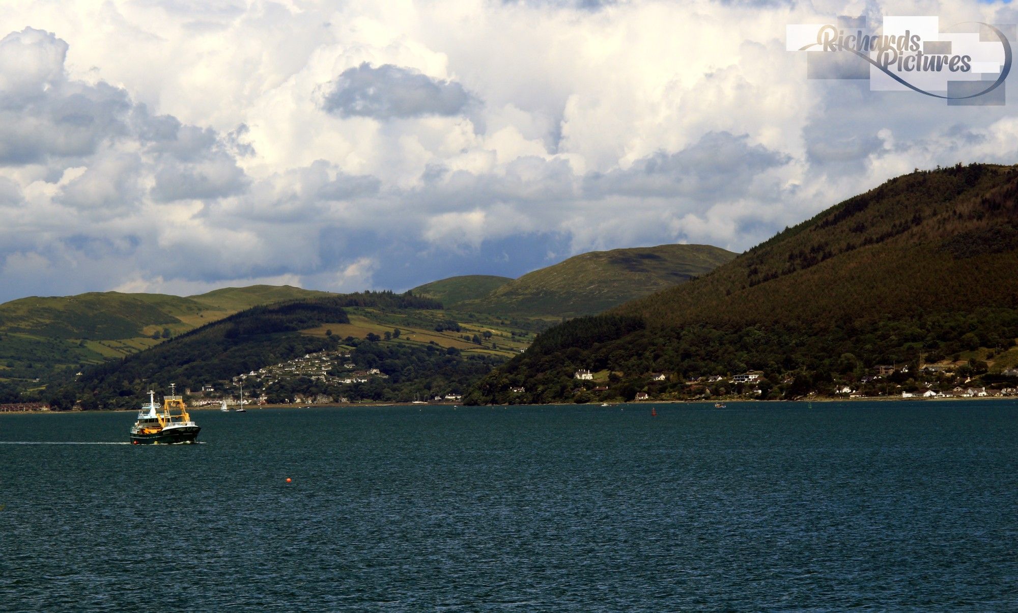 View of Carlingford with a boat on the left. Mountains in the background.