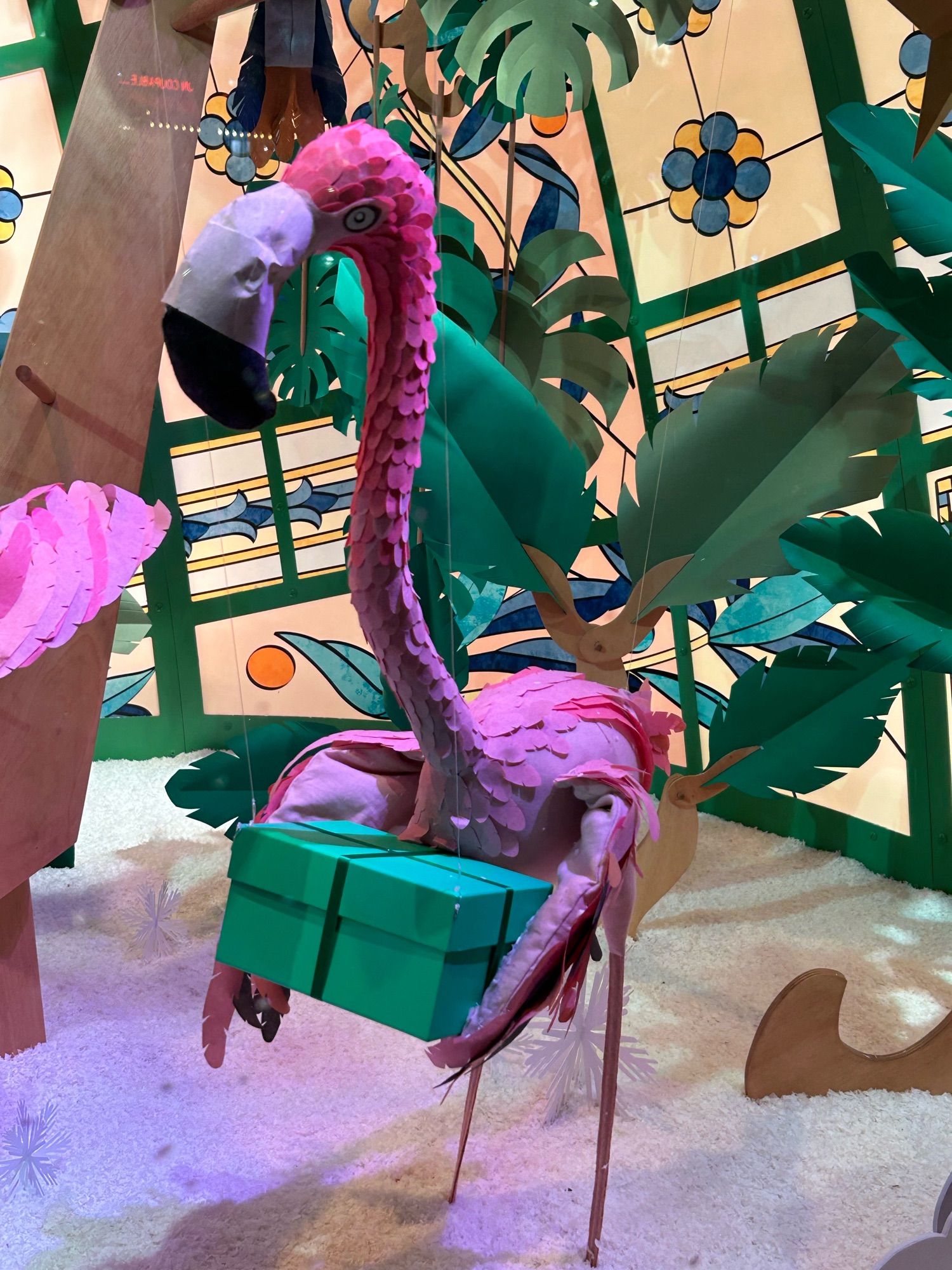 Vitrine de Noël du Printemps (Paris), un mobile en forme de flamand rose tient dans ses ailes un cadeau vert.