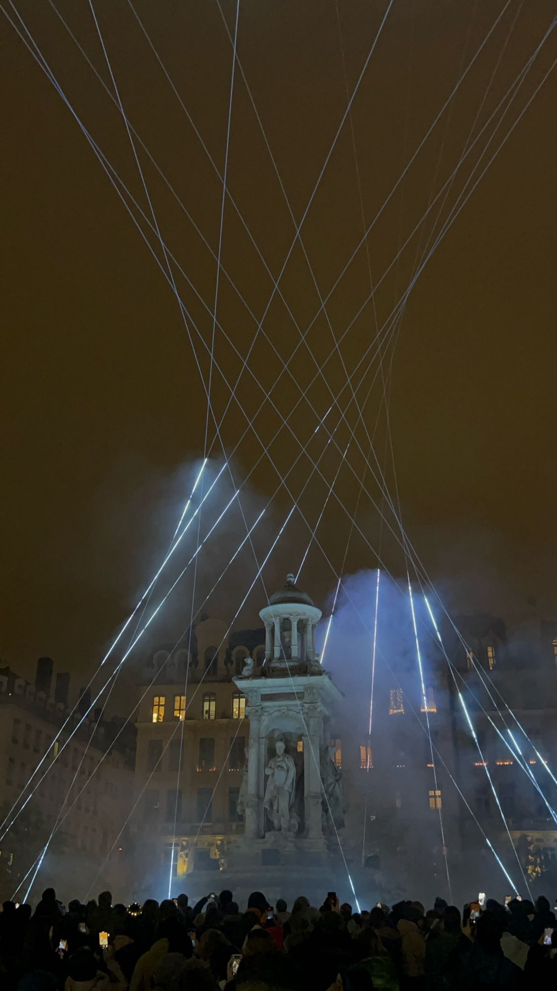 Installation lumineuse pour la fête des lumières autour de la fontaine de la place des Jacobins de Lyon avec des lasers tournant autour.