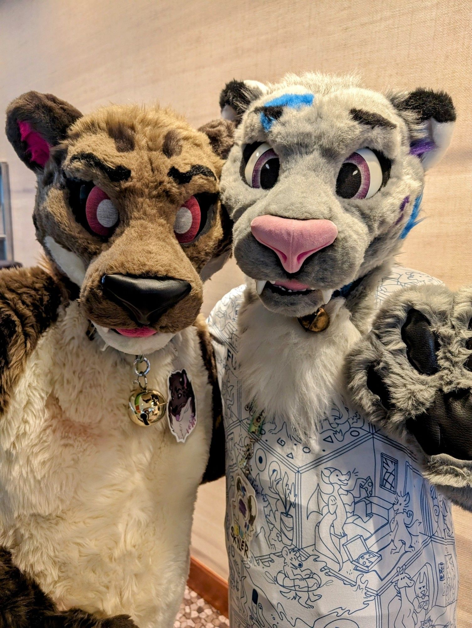 Two snow leopard fursuits, left of picture is brown and tan full suit, right is gray and white partial.