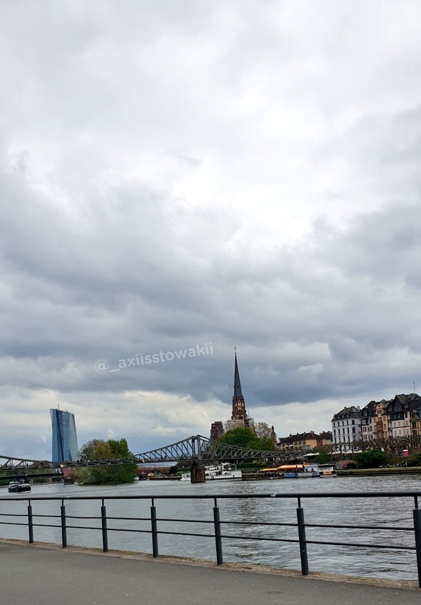 Am Mainufer mit Blick auf die EZB, die Maininsel, den Eisernen Steg und die Dreikönigskirche in Sachsenhausen 
ziehen dunkle Wolken über Frankfurt.