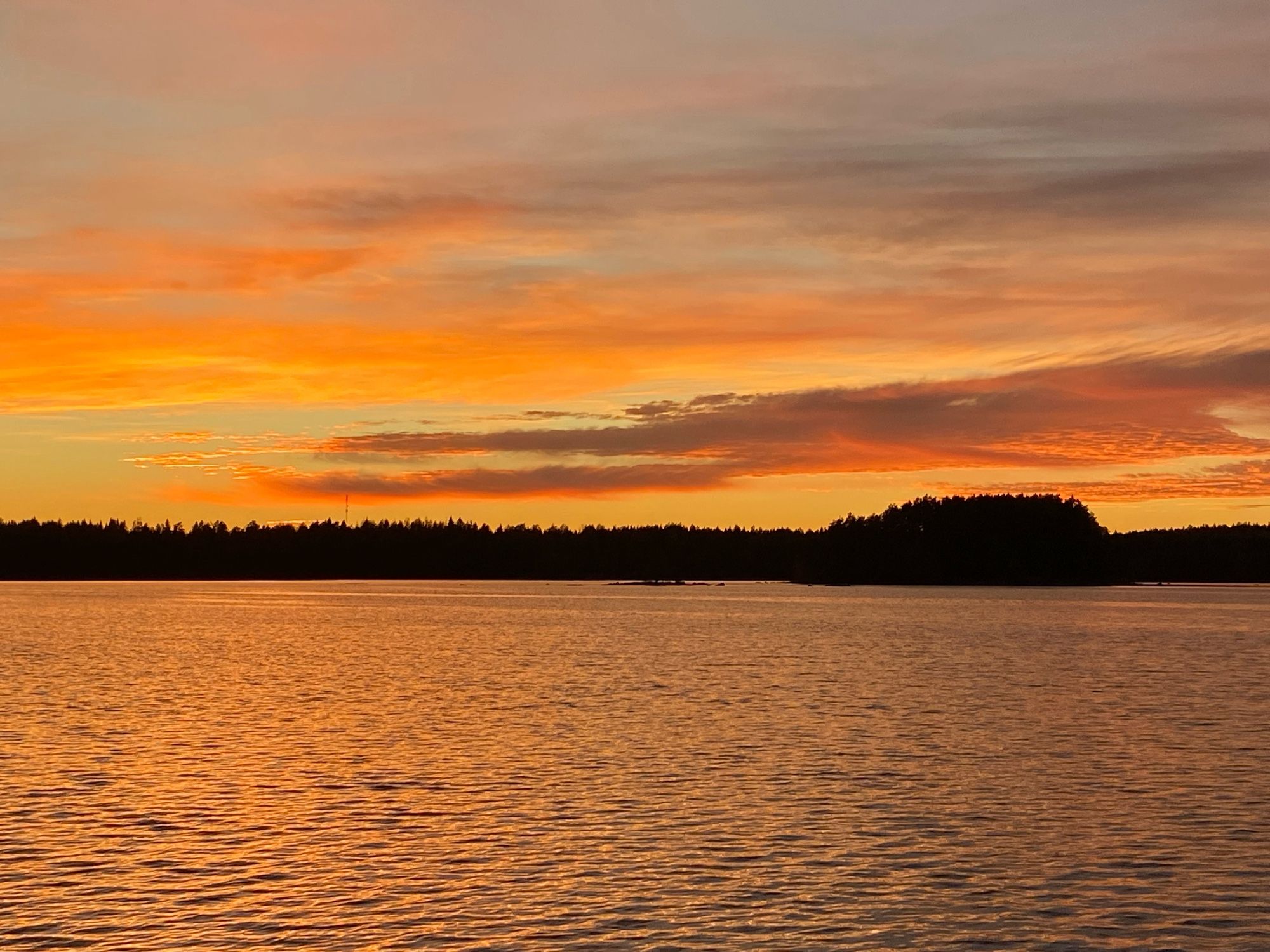 Kullankeltaisenoranssinkirjava järvi auringon laskiessa.