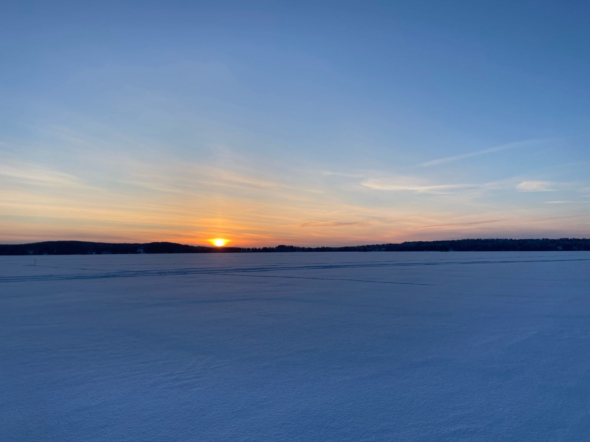 Sinistäkin sinisempi aamun hiihto järvellä. Lentävältä lautaselta näyttävä aurinko nousee takaa ja punaa taivaanrannan. Avaraa.