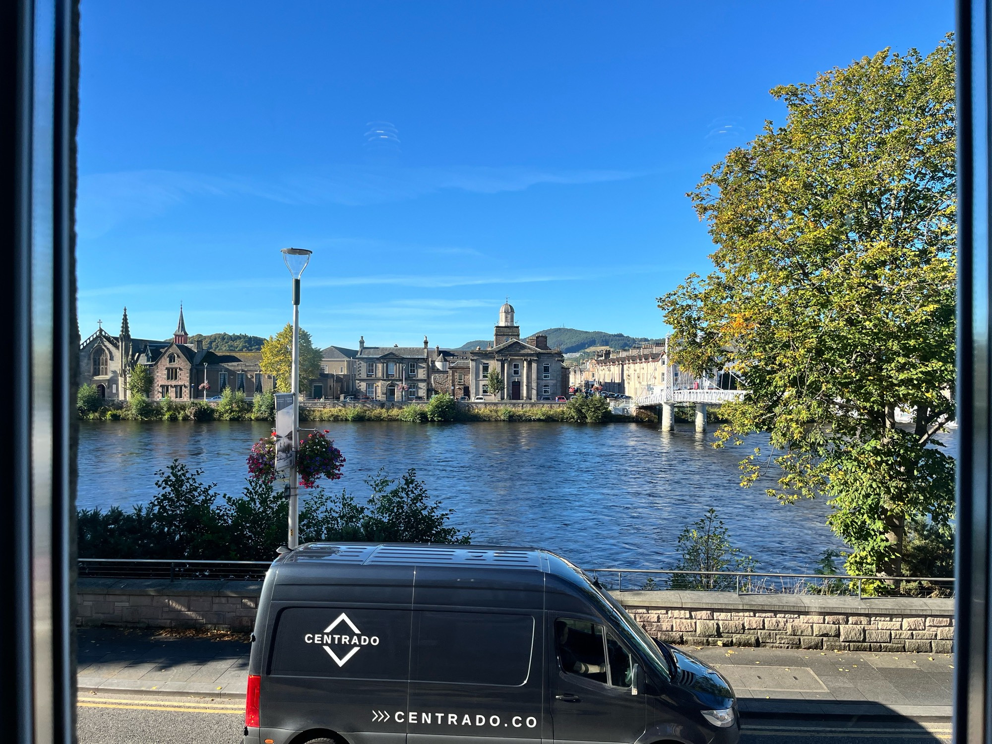 Blue sky over the river Ness with a foot suspension bridge leading to grand Victorian buildings