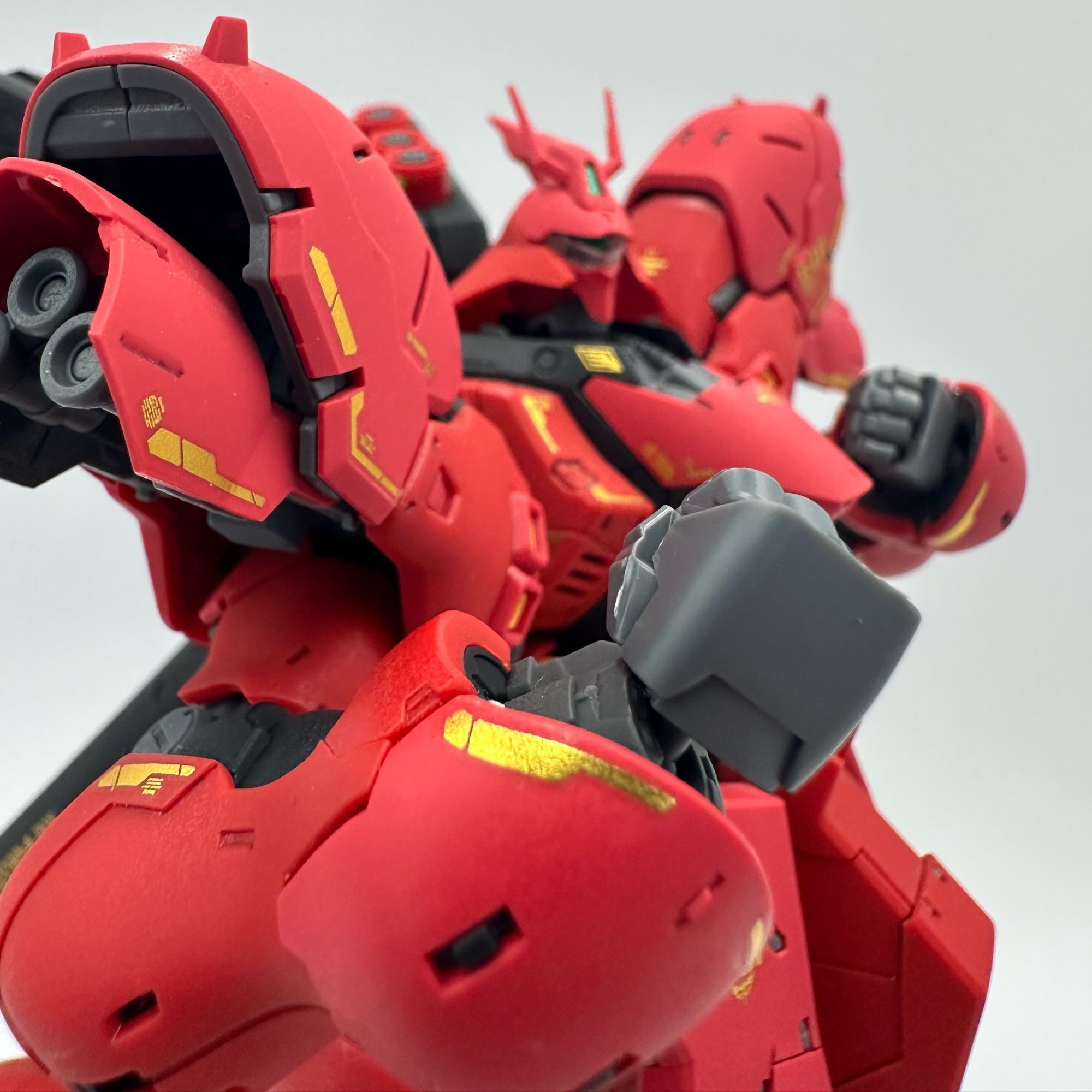 A close up photo of the 1/144 RG Sazabi, with its fist raised like boxing pose. It is suggested it is about to whoop somebody into the ground. 