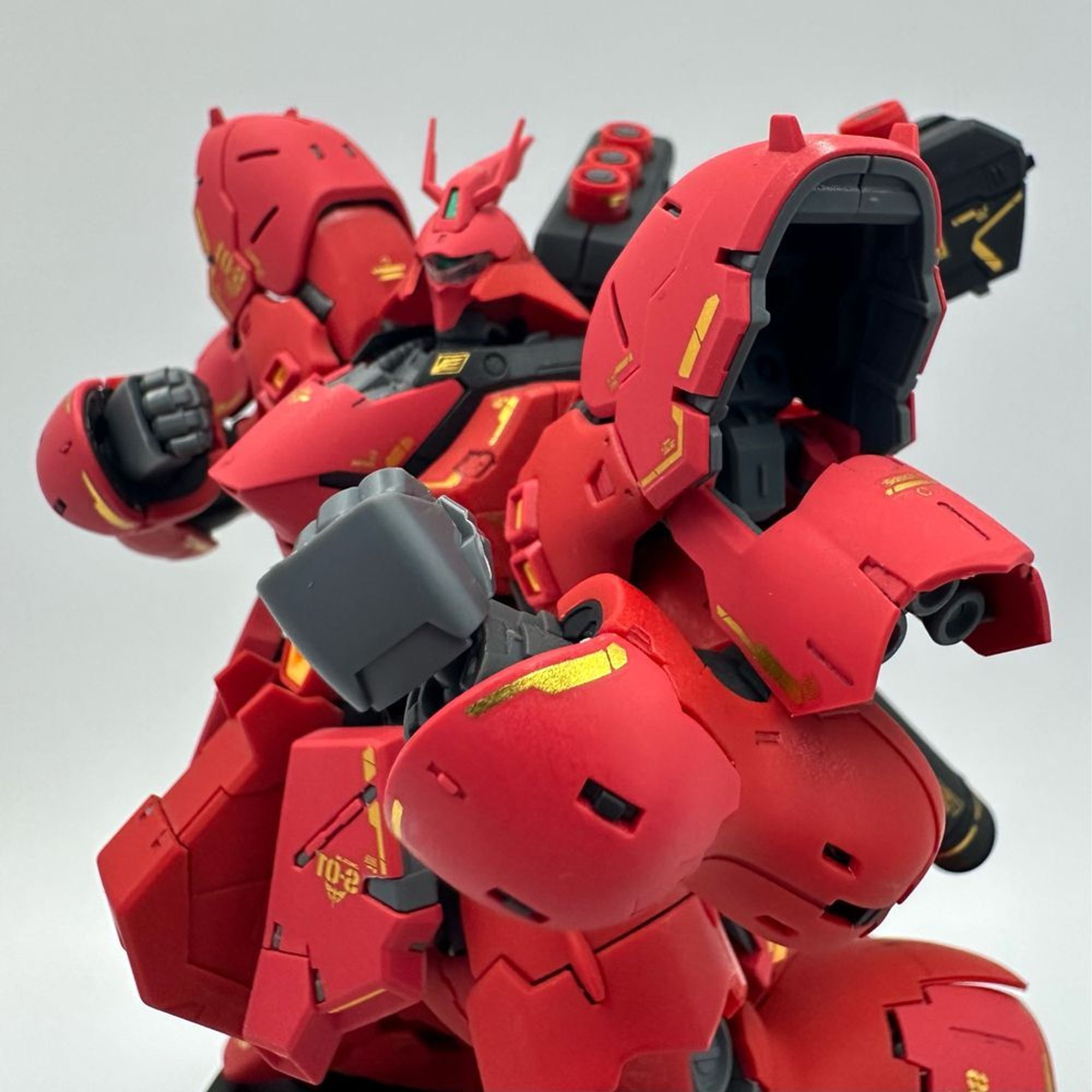 A close up photo of the 1/144 RG Sazabi, with its fist raised like boxing pose. It is suggested it is about to whoop somebody into the ground. 