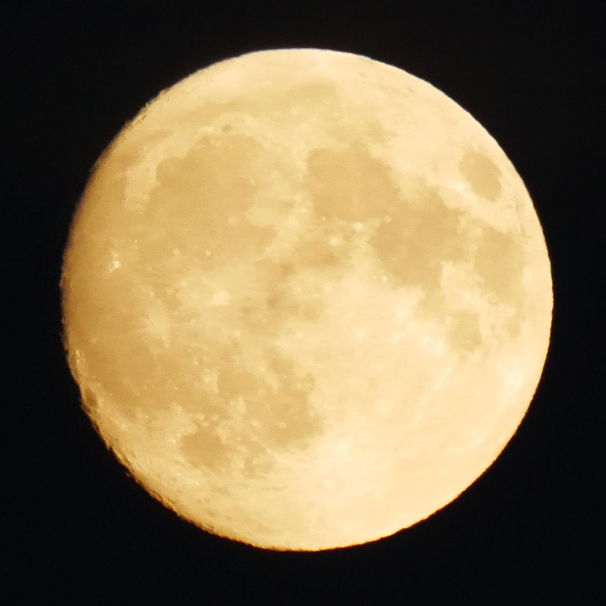 Photo de la lune gibbeuse croissante, éclairée par une lumière dorée. On voit le relief des cratères sur le côté gauche.