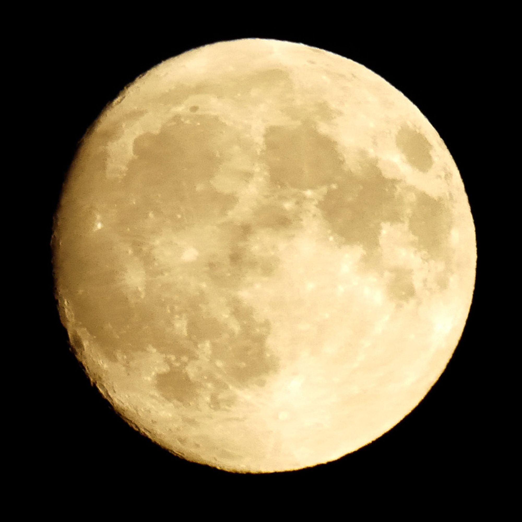 Photo de la lune gibbeuse croissante, éclairée par une lumière dorée, un peu plus foncée que la photo précédente. On voit le relief des cratères sur le côté gauche.