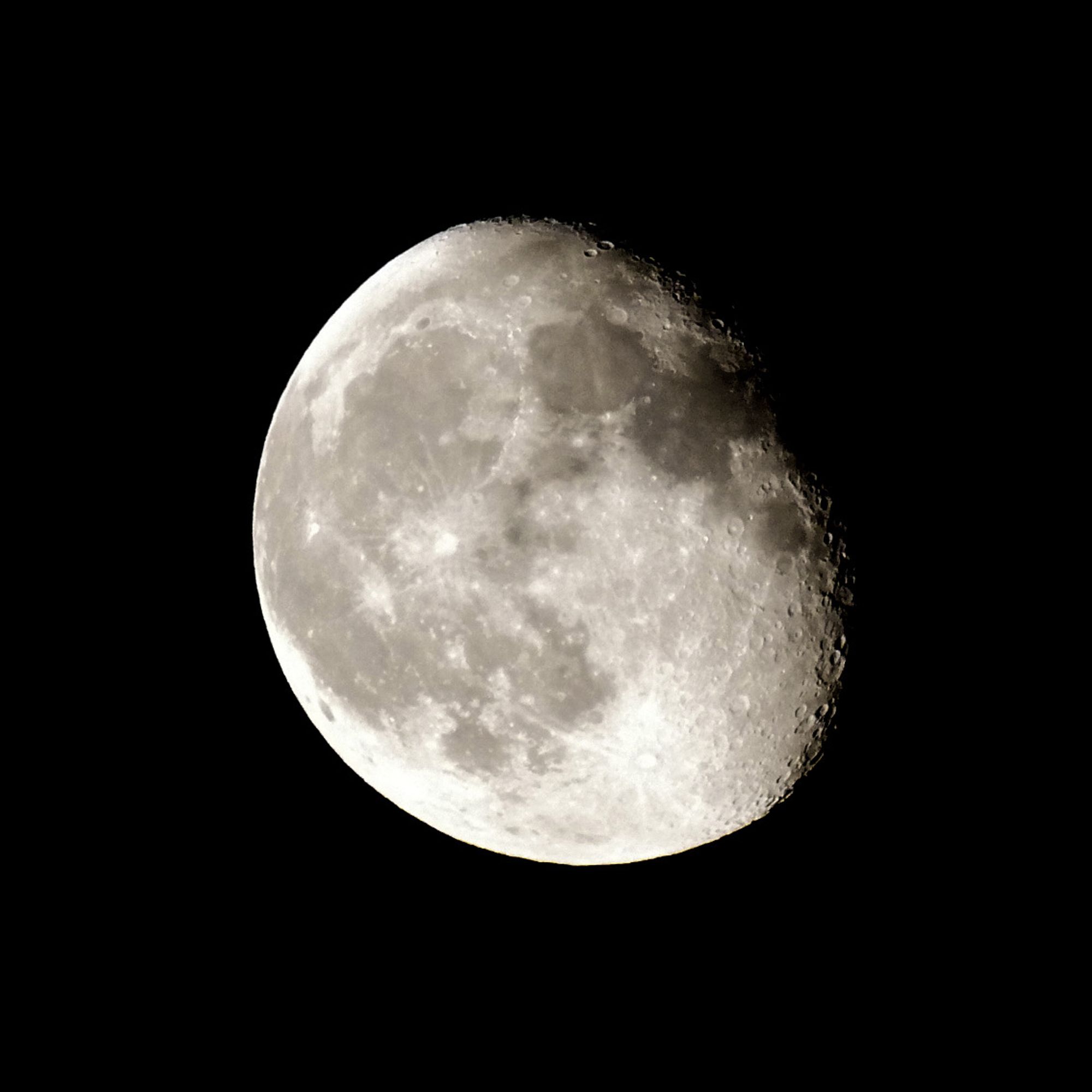 Photo de la lune gibbeuse décroissante, dans les tons de gris. On voit le relief des cratères sur le côté droit.