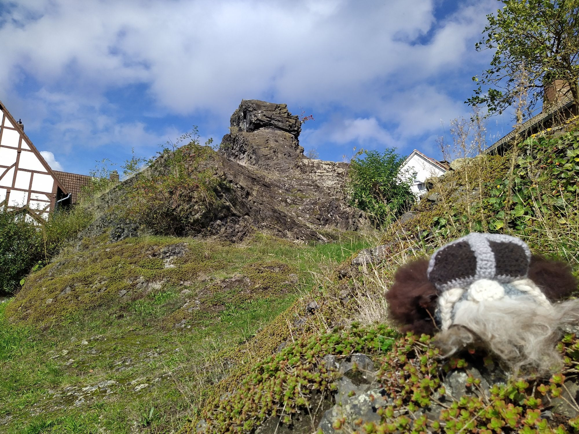 Gehäkelter wikingerkopf auf Felsen, im Hintergrund ein Kegel aus dunkelgrauem Basalt Gestein