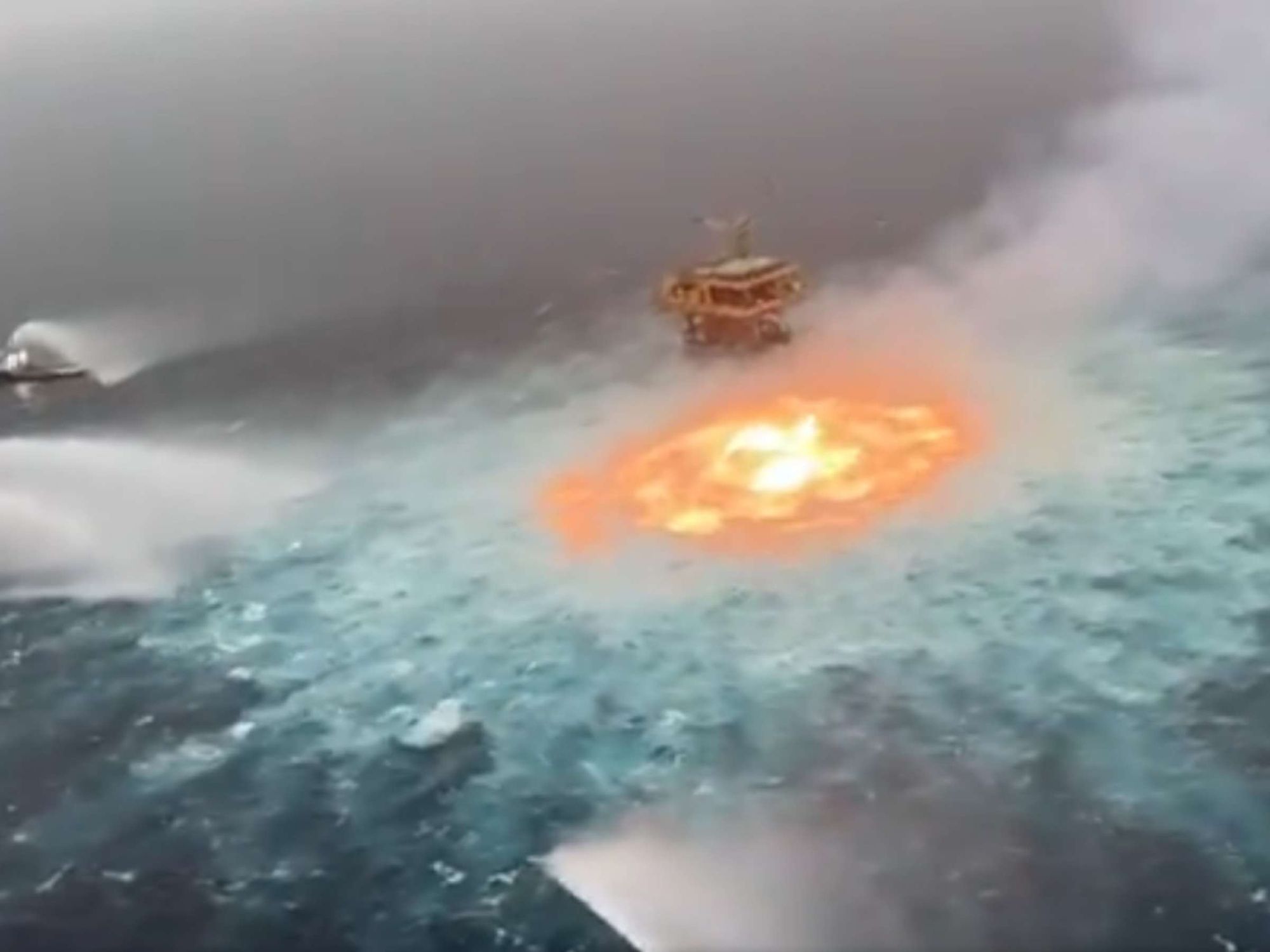 Foto der Öl-Bohrplattform Deepwater Horizon und wie vor ihr der Gas-Blowout brennt.