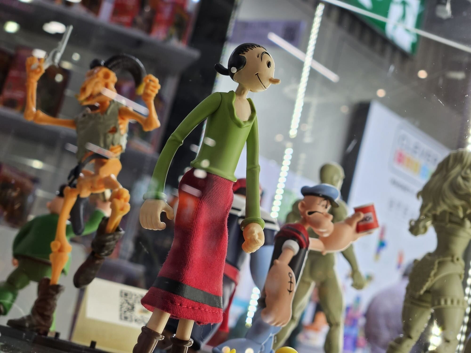 A nearly dutch angle shot of our display case from Nuremberg toy fair featuring samples of the Power Stars Olive Oyl and Popeye figures.