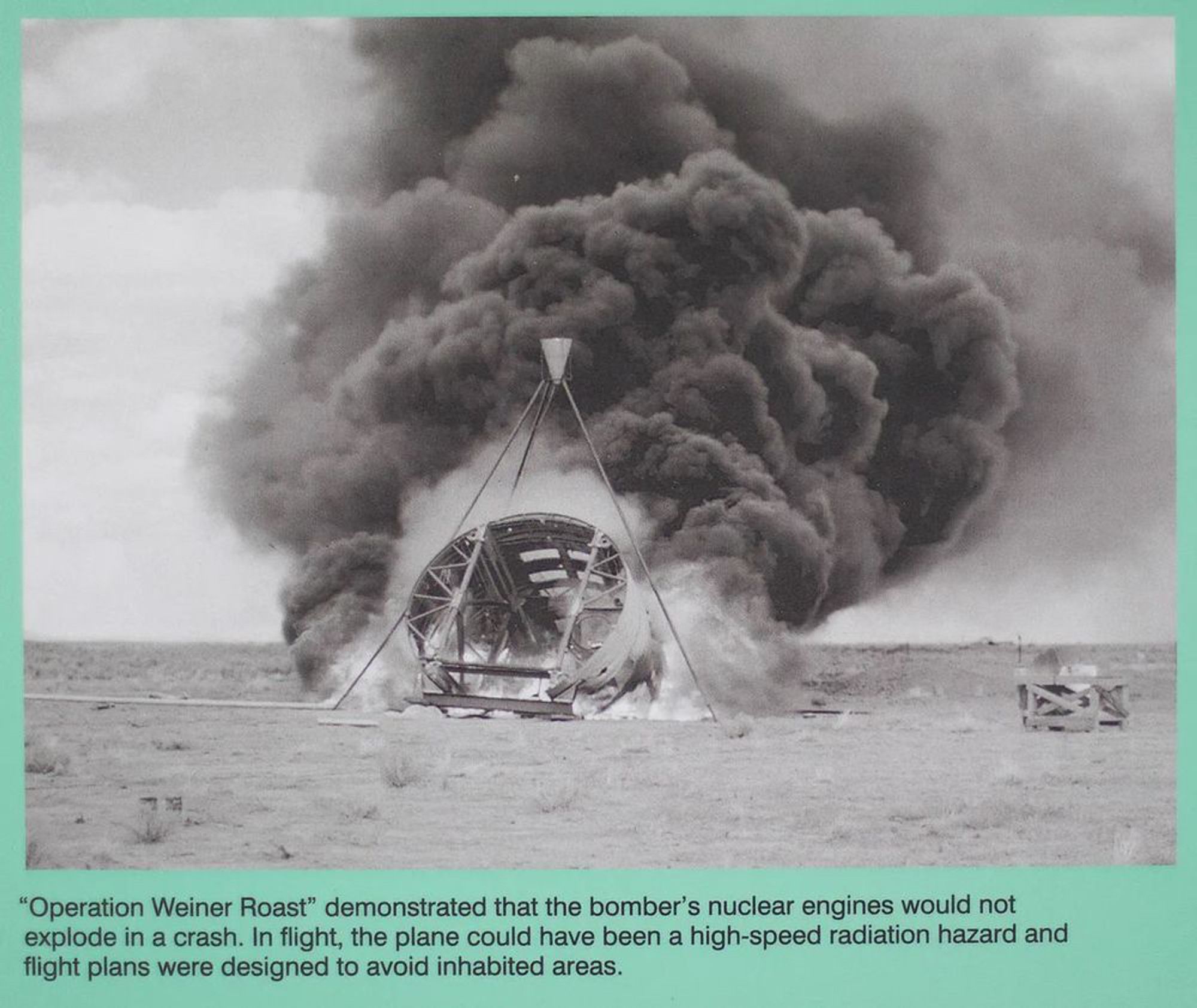 A black and white ground-level photograph of the “Operation Weiner Roast” experiment showing a fire and a large cloud of billowing black smoke.