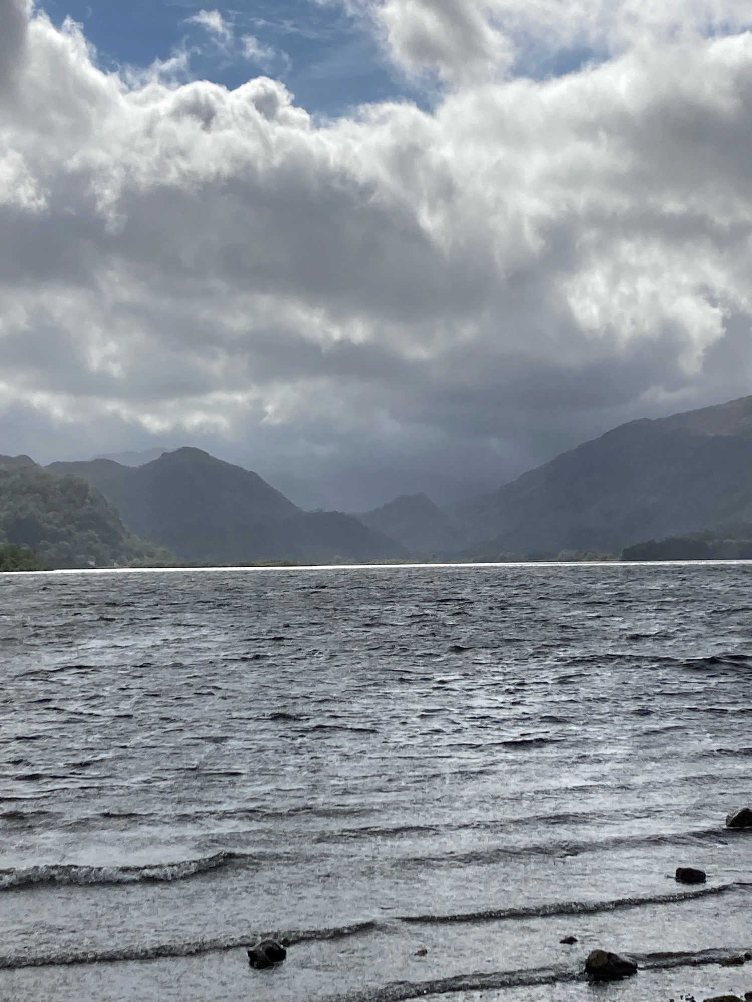 Light on lake with backdrop of fells and dark cloud