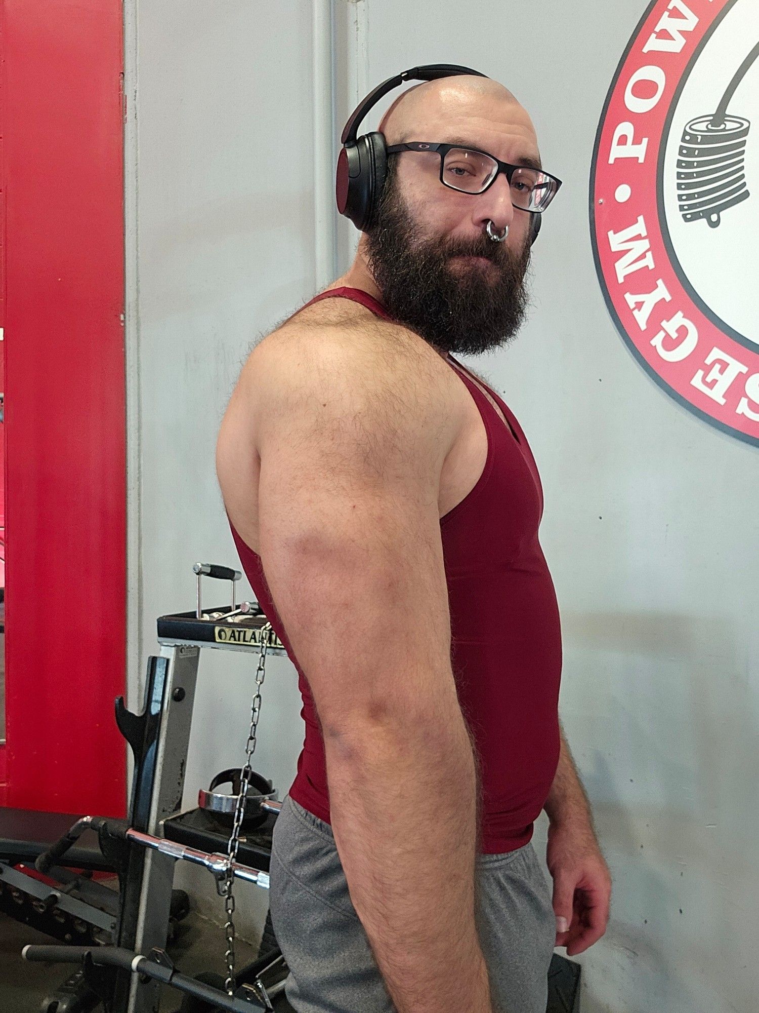 Kunai flexing his tricep in a red tank after a workout