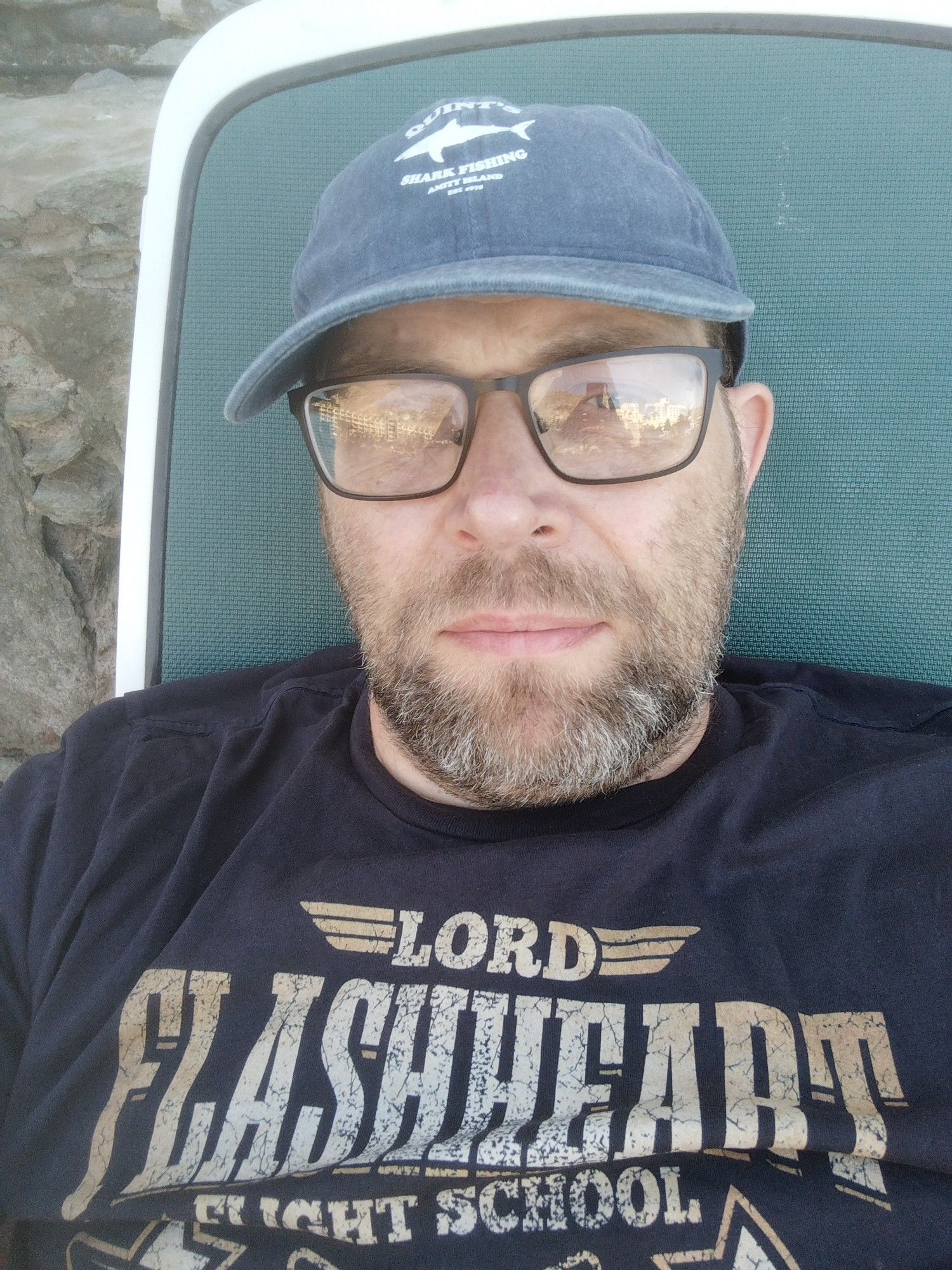 Me wearing a Quints Shark Fishing baseball cap and a Lord Flasheart Flying School t shirt. 
I am on a sunlounger on holiday not doing much.