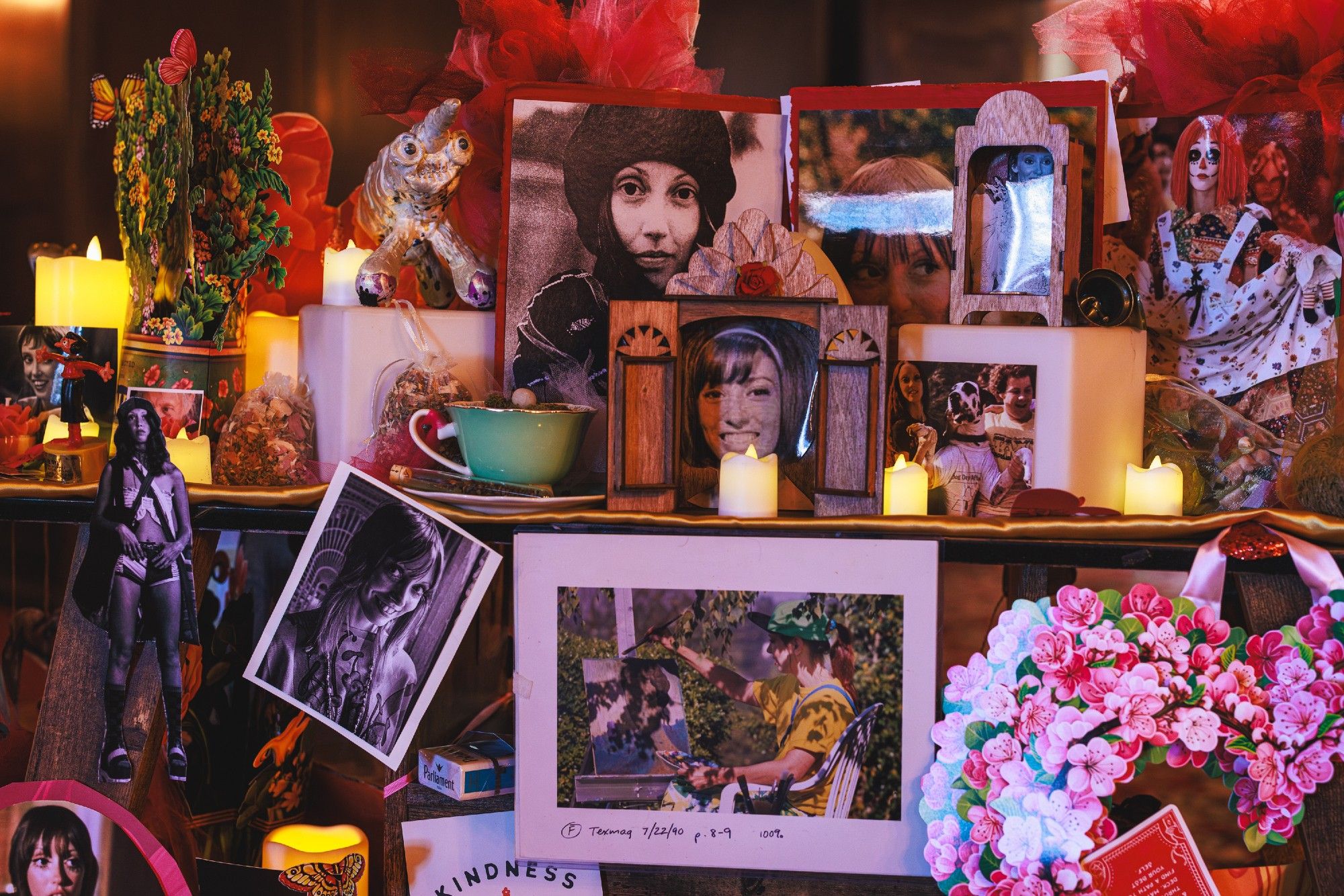 A photo of an altar consisting of many printed pictures of Shelley Duvall and small LED candles and other random items arranged on shelves.