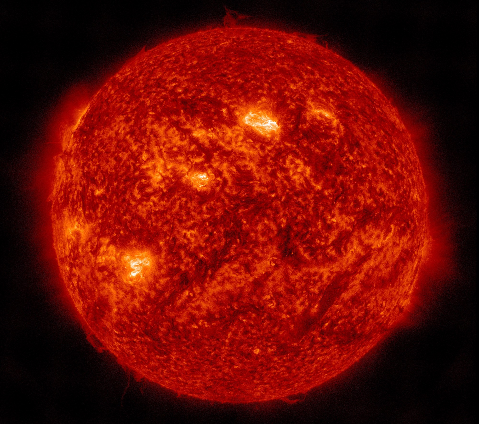 Die ganze erdzugewandte Seite der Sonne in orangeroter Farbe. Drei Aktive Regionen ungefähr in der Mitte sowie schräg rechts darüber und schräg links darunter so ähnlich wie bei der Drei auf einem Würfel angeordnet sind in helleren Gelbtönen wiedergegeben. Vor allem links am Rand ein Saum aus Strahlung, drumherum das Schwarz des Alls.