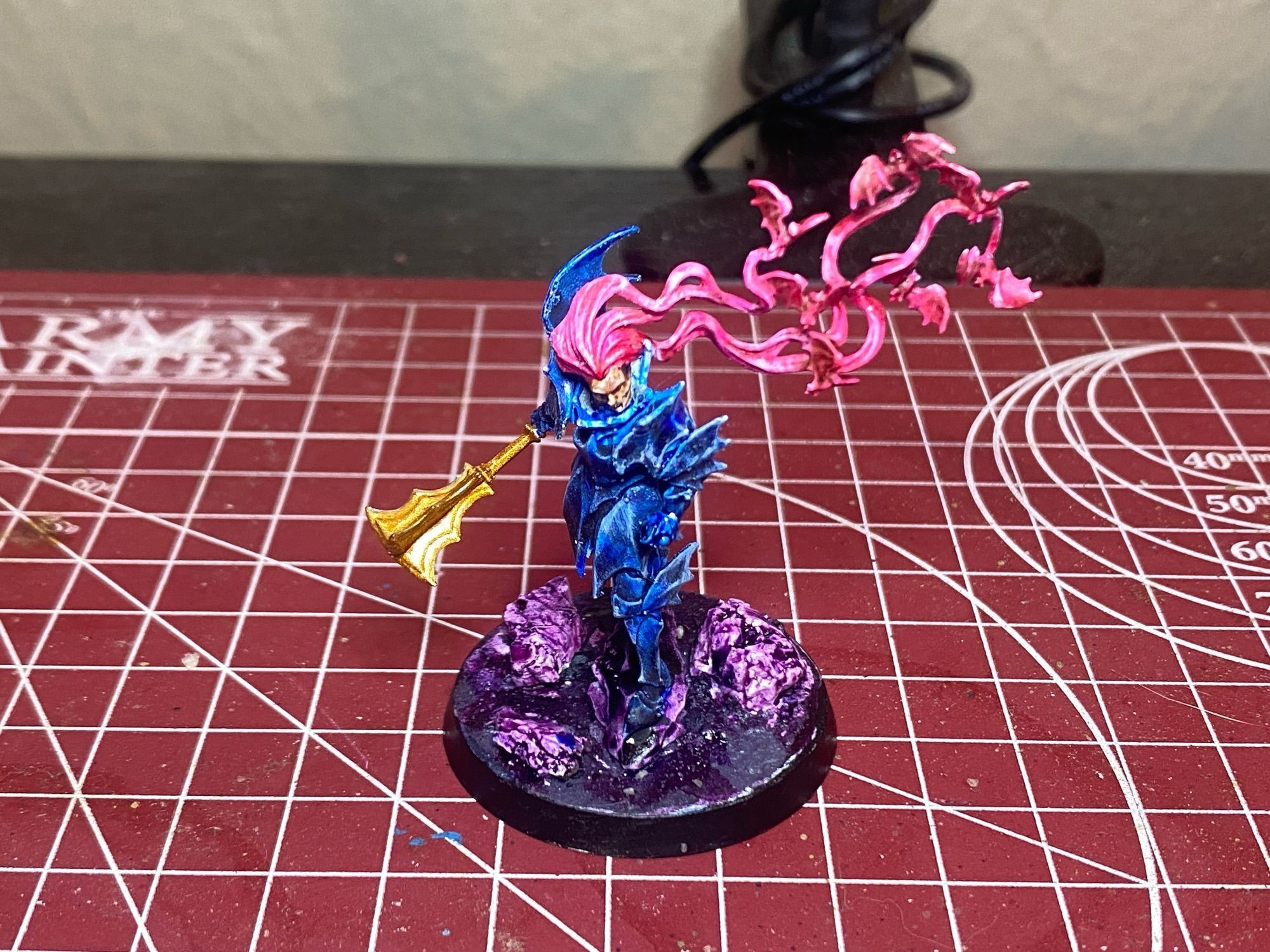 painted vampire lord from games workshop age of sigmar range.

the base is covered with rocks, all painted purple. the armor is painted blue. the mace is painted gold. the hair has bats in it, all painted pink.