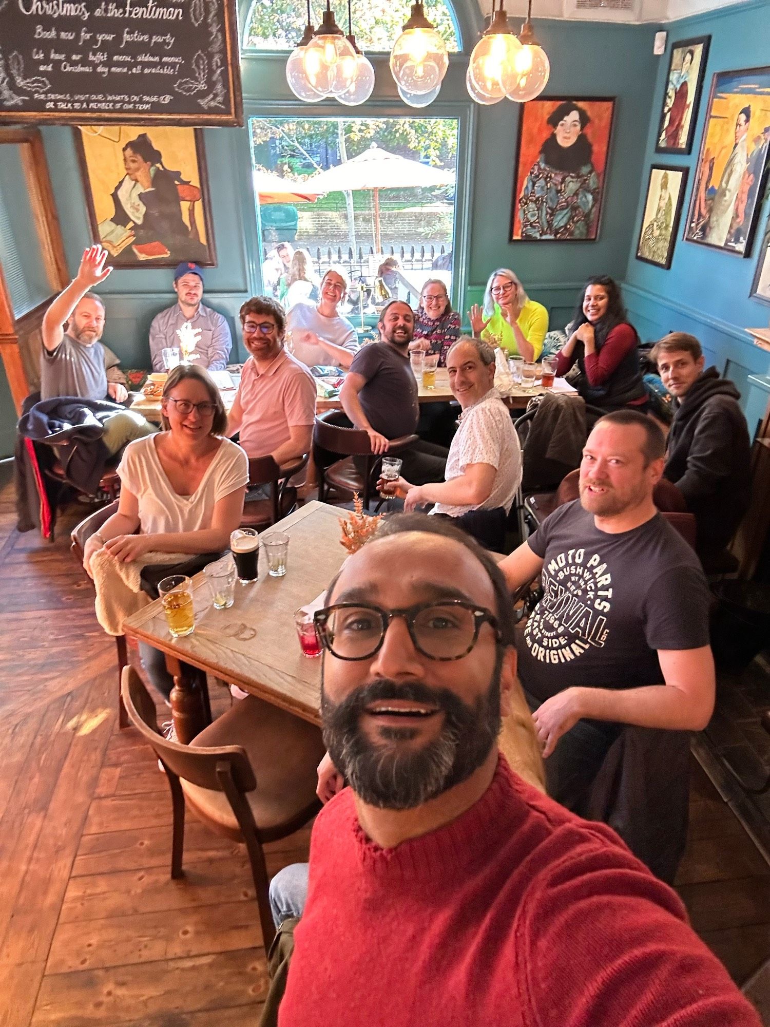 Group of people sat in pub with me in foreground taking selfie.