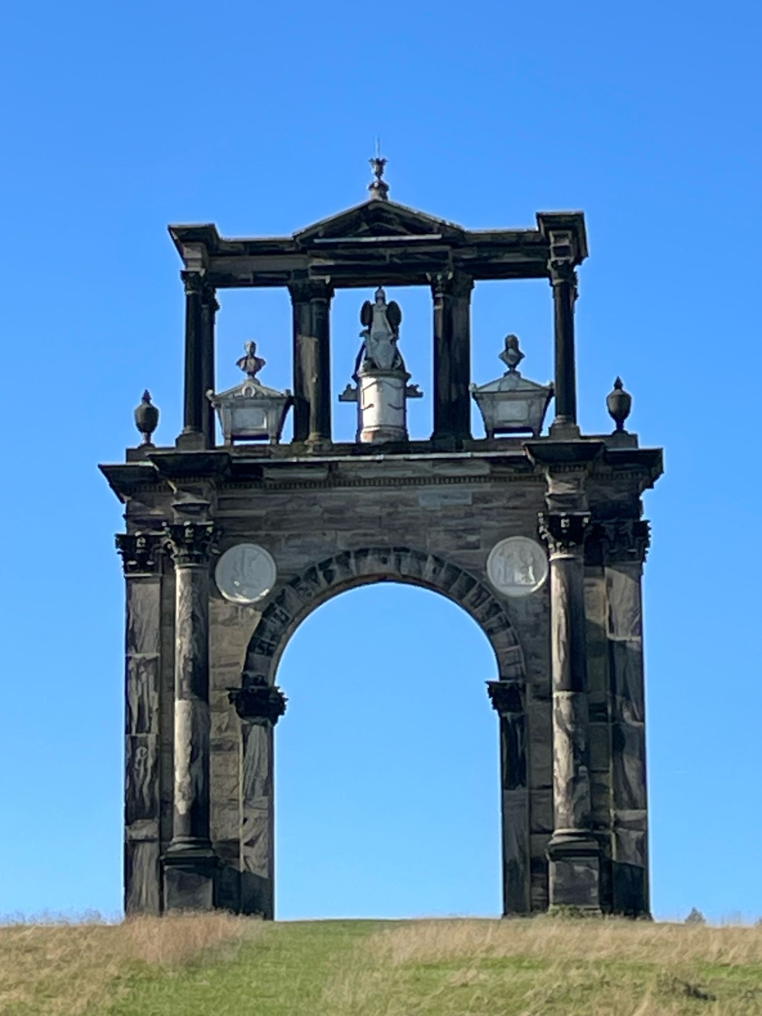 View of Hadrian’s Arch, Shugborough: erected in the 1760s and modelled on the original in Athens; set against a blue sky.