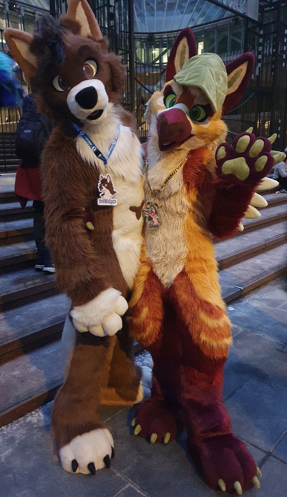 A cream and brown wolf on the left posing with a yellow and brown gryphon with a leaf on his head