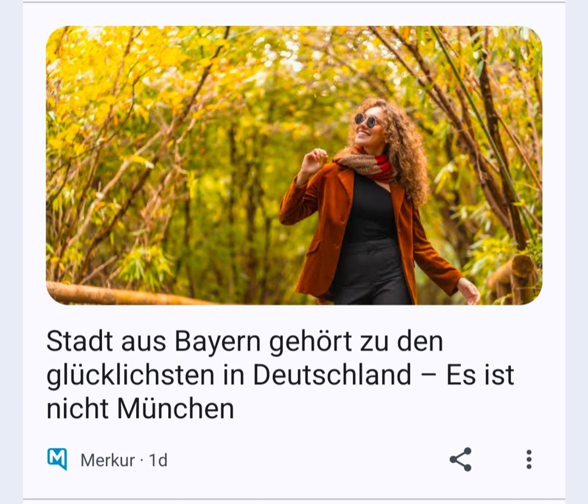 Merkur Schlagzeile: Stadt aus Bayern gehört zu den glücklichsten in Deutschland – Es ist nicht München. Darüber ein Bild einer Frau die etwas dazu glücklich in einem Herbstwald spazieren geht