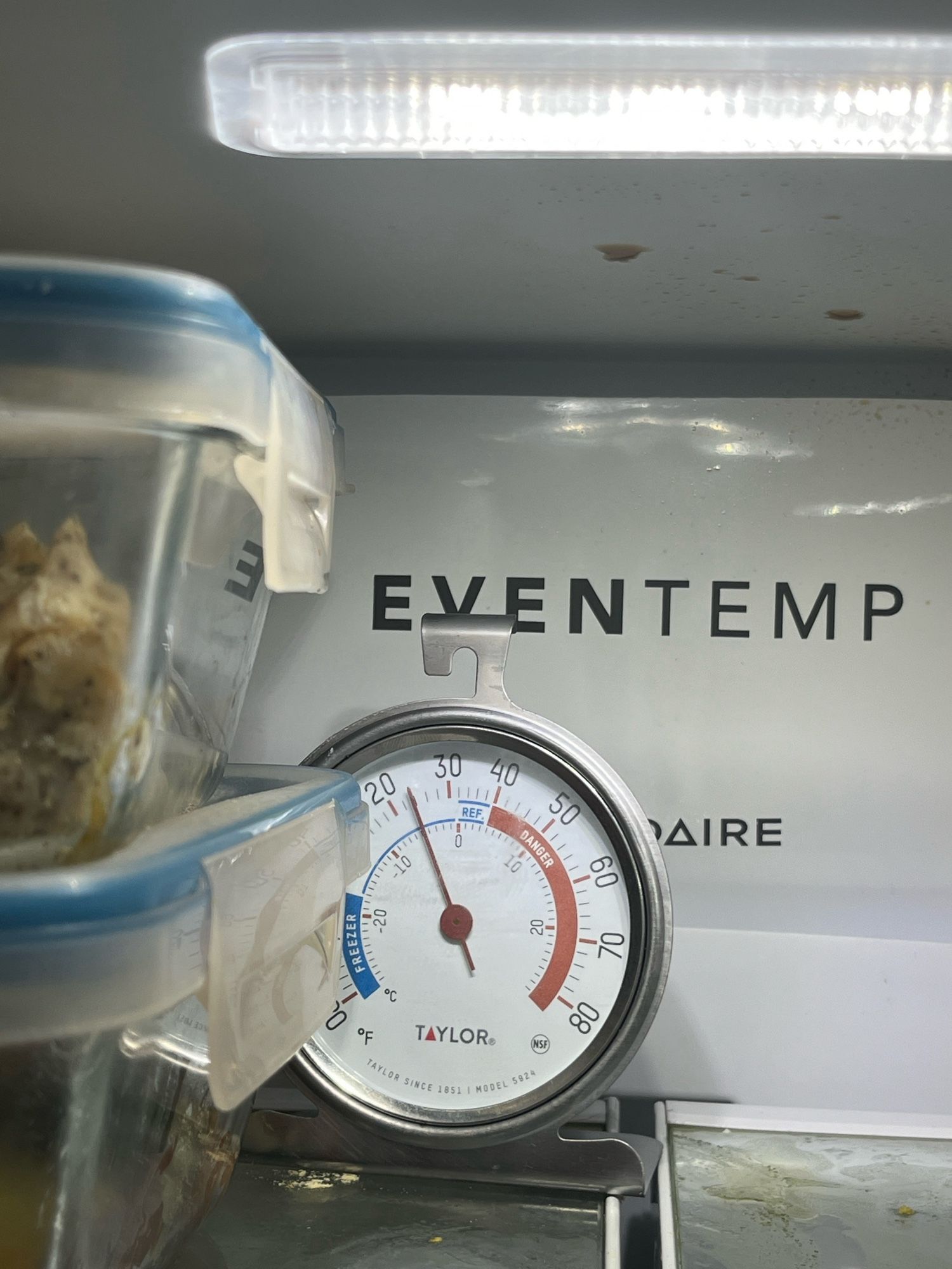 A thermometer reads 20 degrees in front of the back wall of my fridge that says “EVENTEMP.”