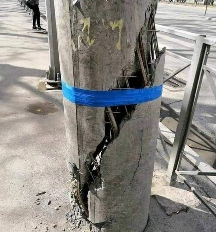 Cement post crumbling apart and being held together with blue tape 