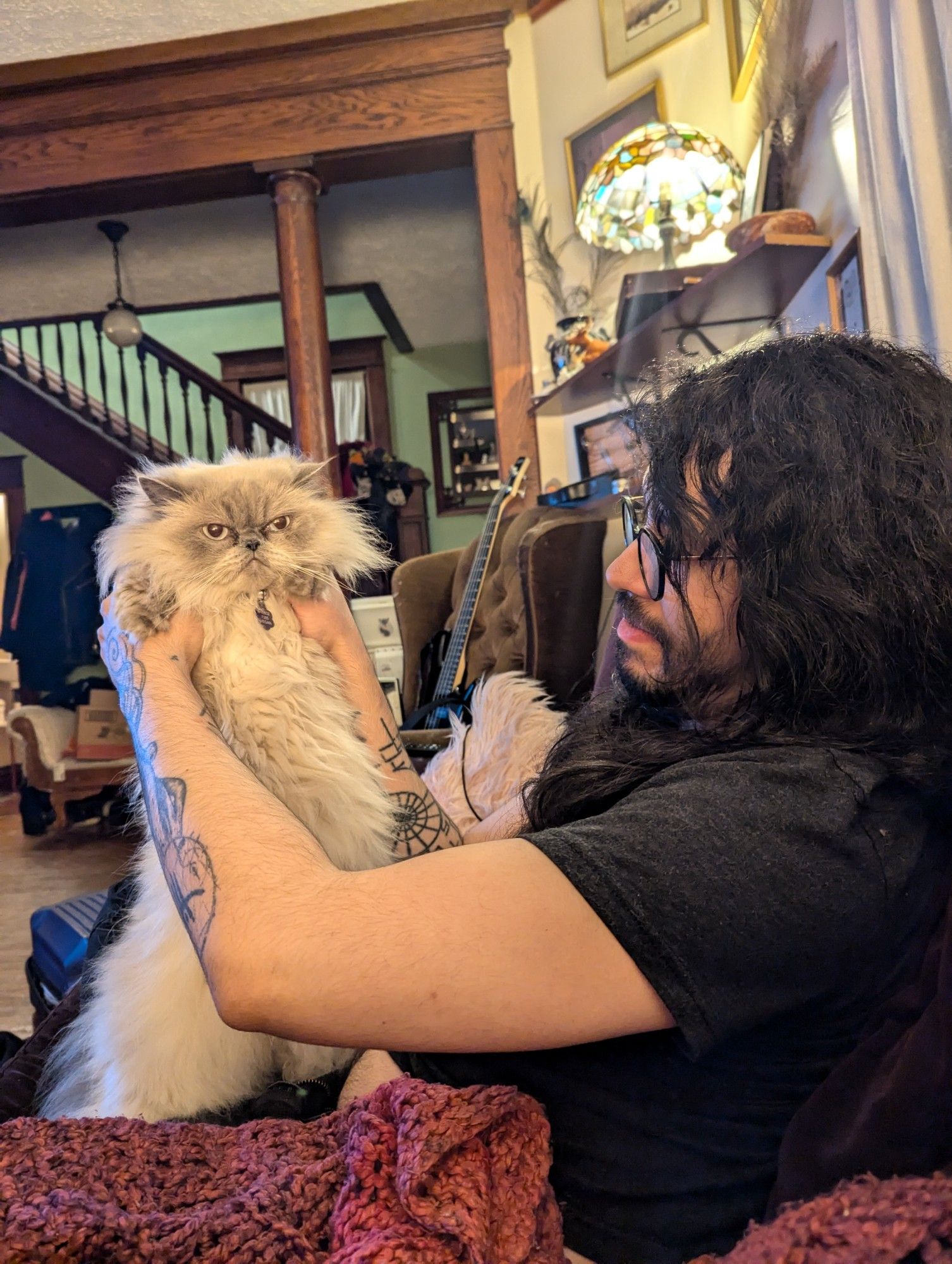 Goth boyfriend holds up Egg, our Himalayan cat who is simmering with barely contained yet impotent rage