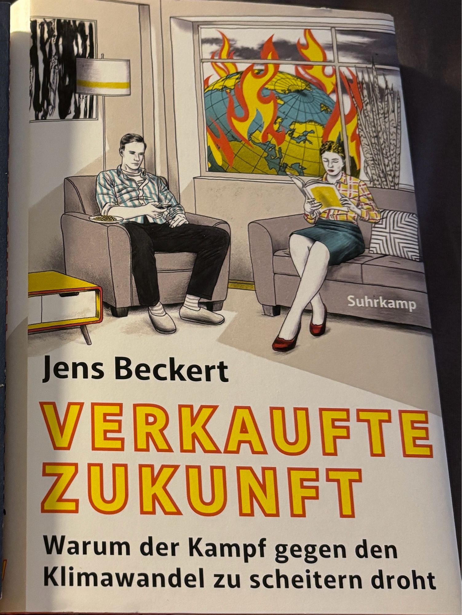 Buchcover des Buches „Verkaufte Zukunft —Warum der Kampf gegen den Klimawandel zu scheitern droht“ von Jens Beckert. Frau und Mann sitzen gemütlich im Wohnzimmer und lesen/schauen Fern. Draußen vor dem Fenster ein brennender Globus.