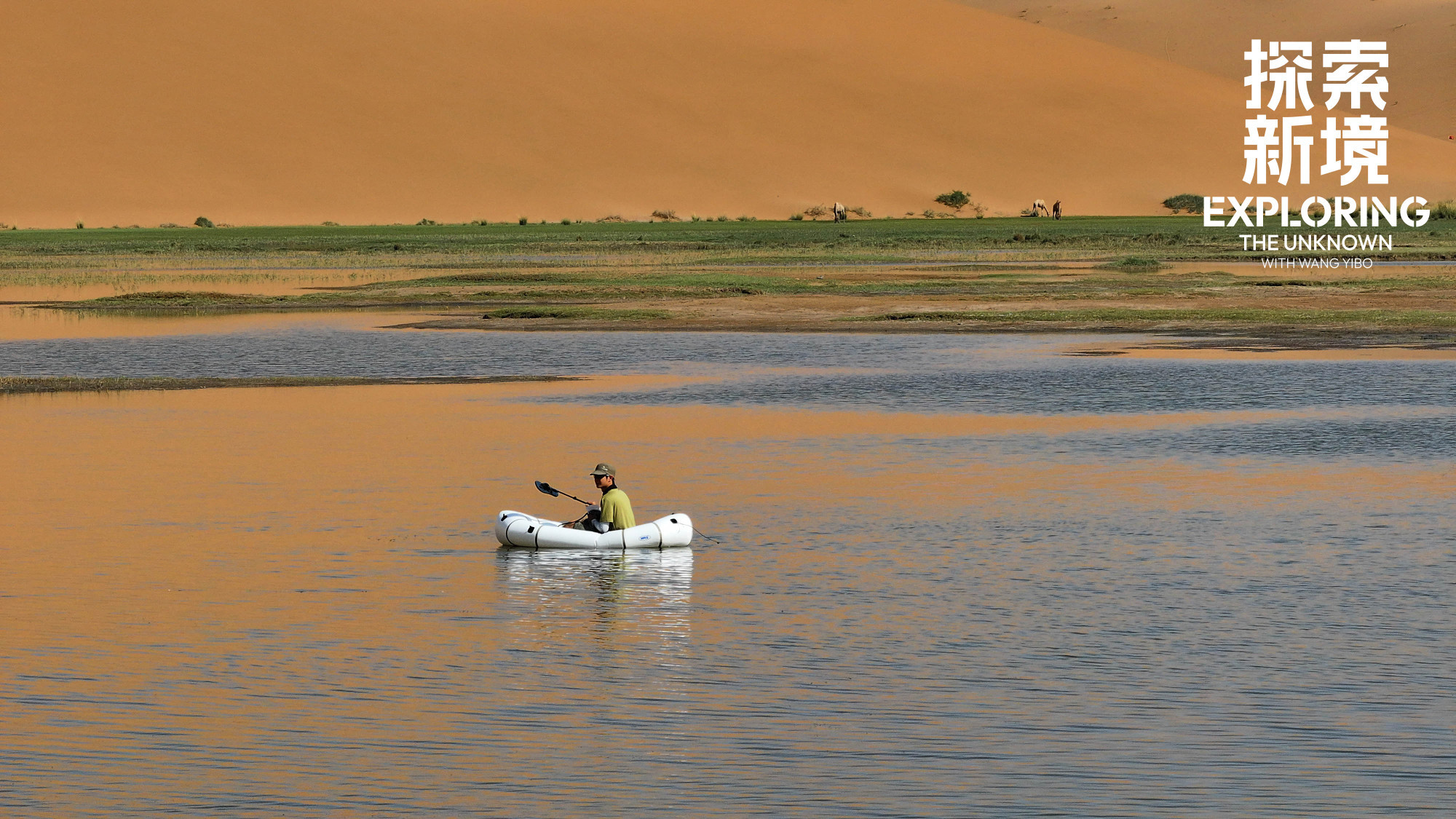 #WYB in the distance in a white dinghy, on a lake, in the desert, with golden brown light reflected on the water around him.