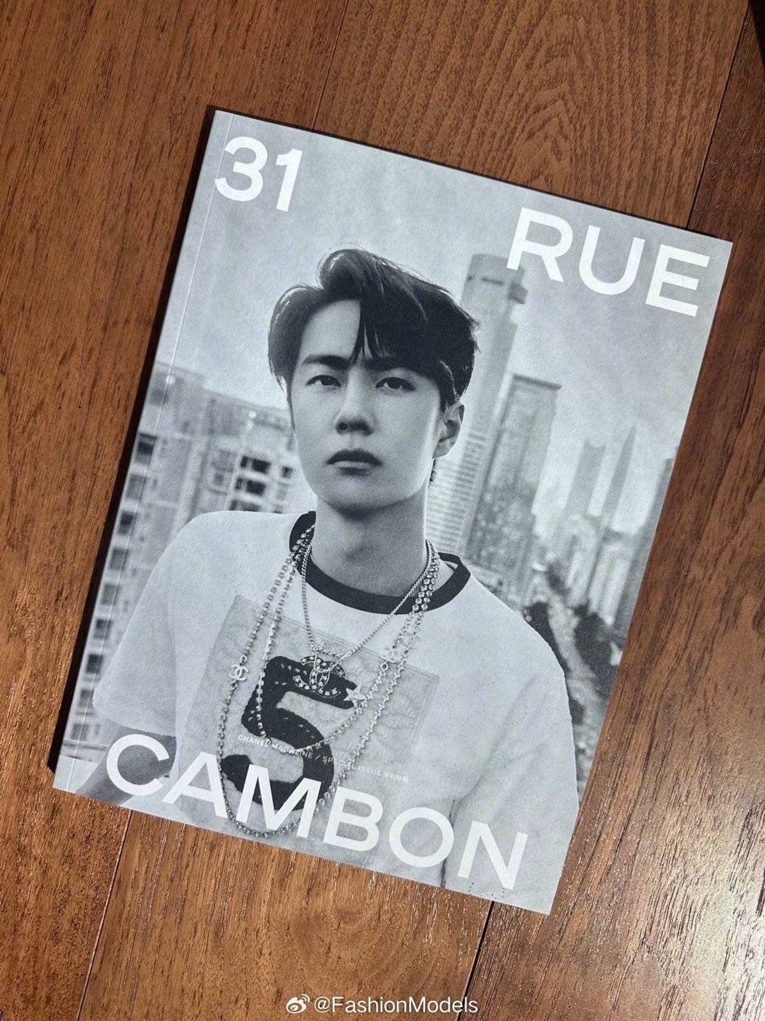 a magazine lying on a wooden surface. The magazine has a b&w photo of WYB in the #5 crop top and multiple necklaces, looking down the barrel of the camera, with white lettering over the top reading: 31 RUE CAMBON

Watermark on the picture shows it was taken from weibo account @FashionModels