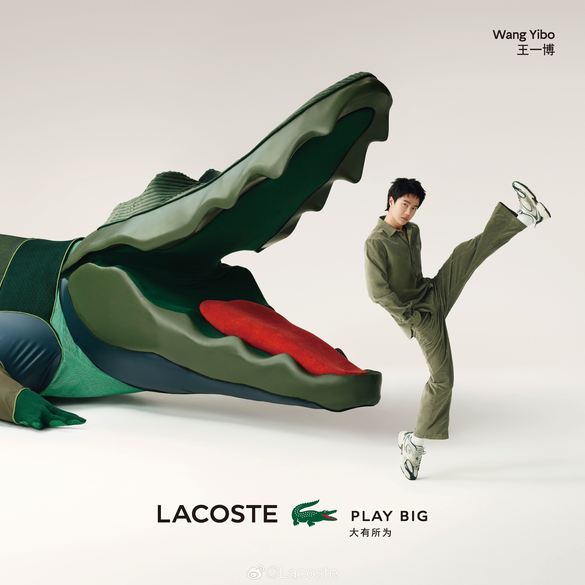 WYB in green athleisurewear, hands in pockets, enpointe on his right besneakered foot, while his left ensneakered foot kicks as high as his head. This image superimposed on a picture of an enormous model crocodile.